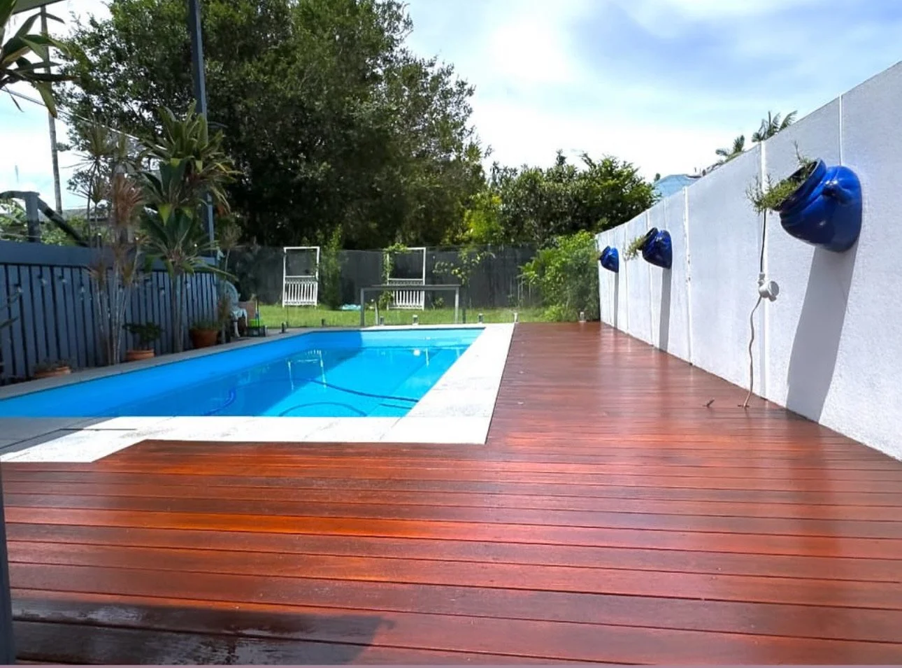 The finished pool deck after re-coating, boards a deep red-brown in the sun