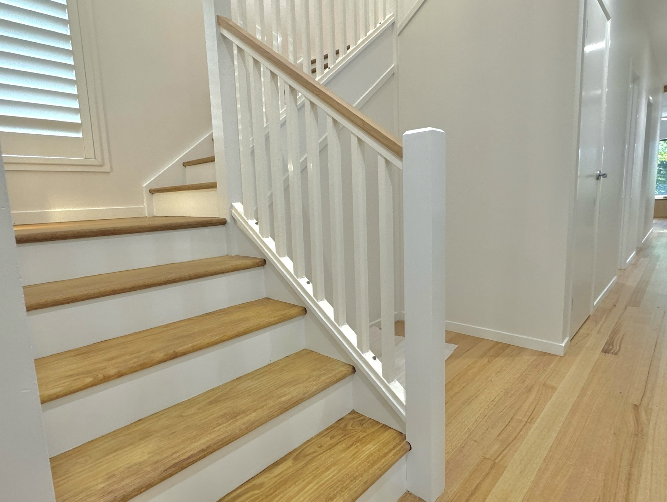 Interior view of a staircase with wooden steps and a white railing in a house