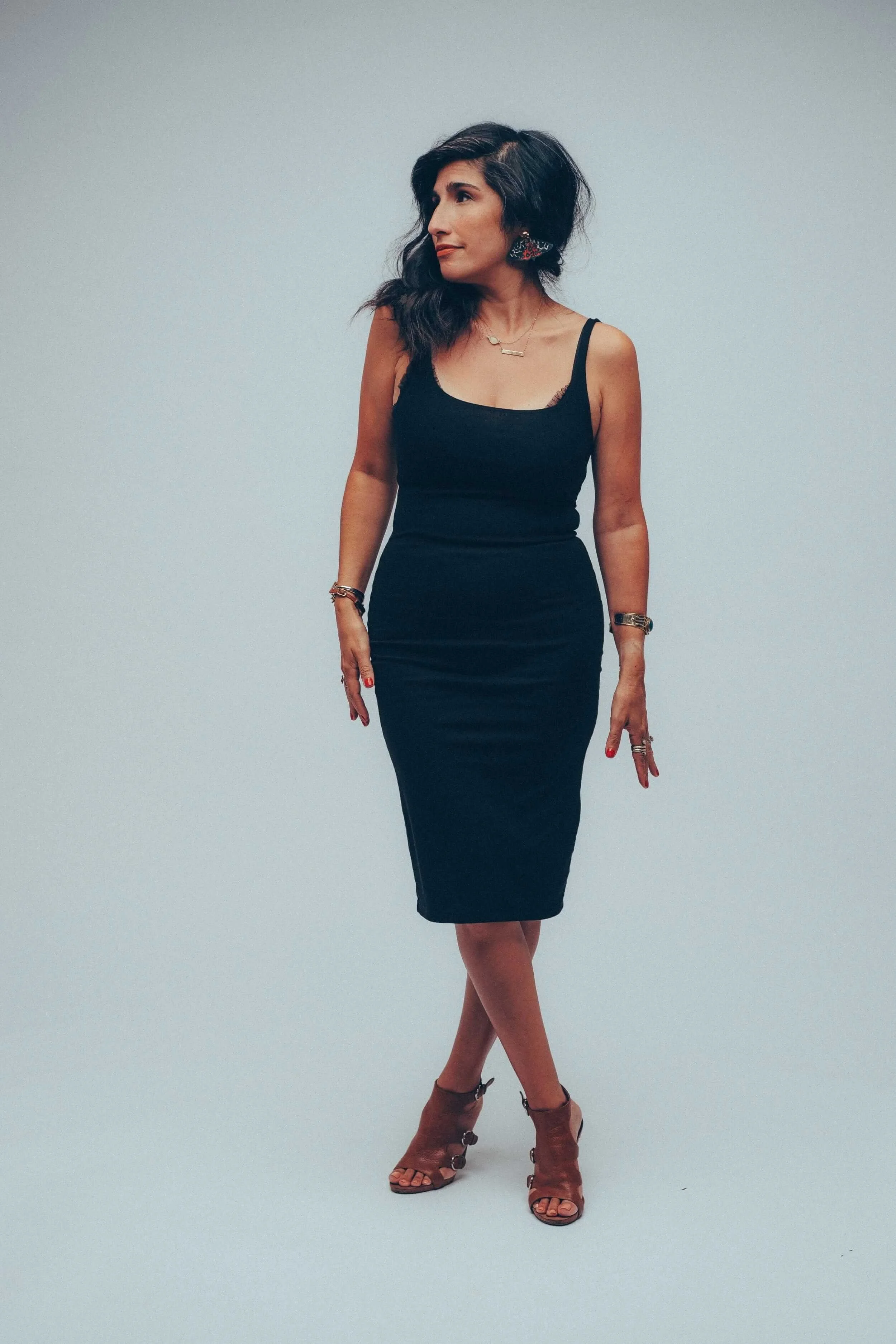 Elizabeth Quintal in a black dress standing with legs crossed and looking to the side