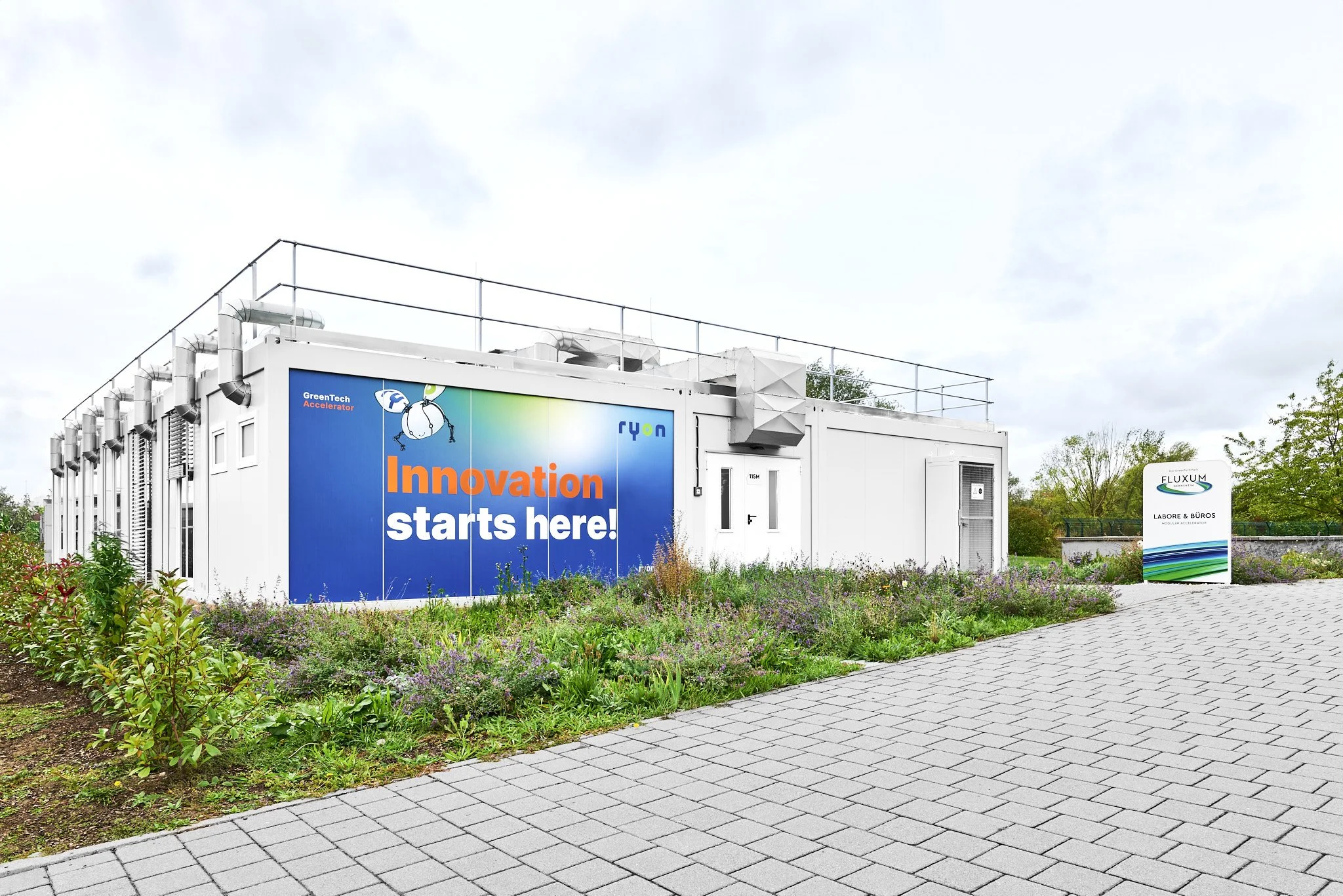 NBR Innovation Hub Gebäude mit technischer Außenstruktur, GreenTech Accelerator Branding und FLUXUM Labore-&-Büros Kennzeichnung.