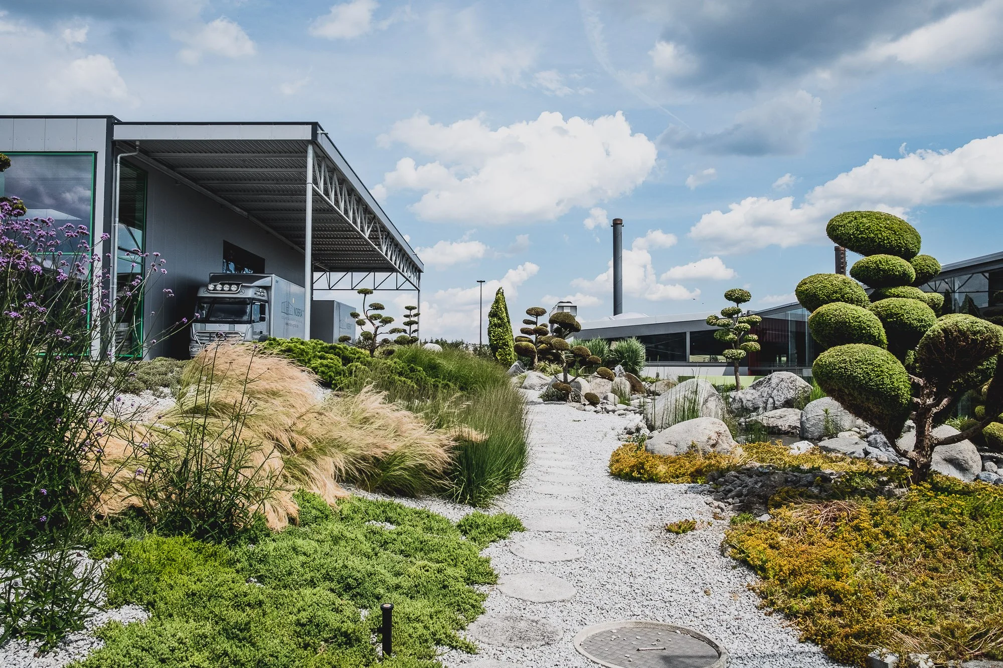 NOBRA GmbH: Moderne Recycling- und Rohstoffrückgewinnungsanlage mit großem Ladebereich, wartendem LKW und gepflegter Grünanlage auf dem Betriebsgelände.
