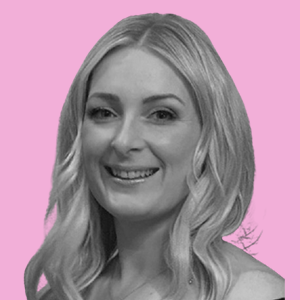 A woman with long blonde hair smiling, with a pink background.