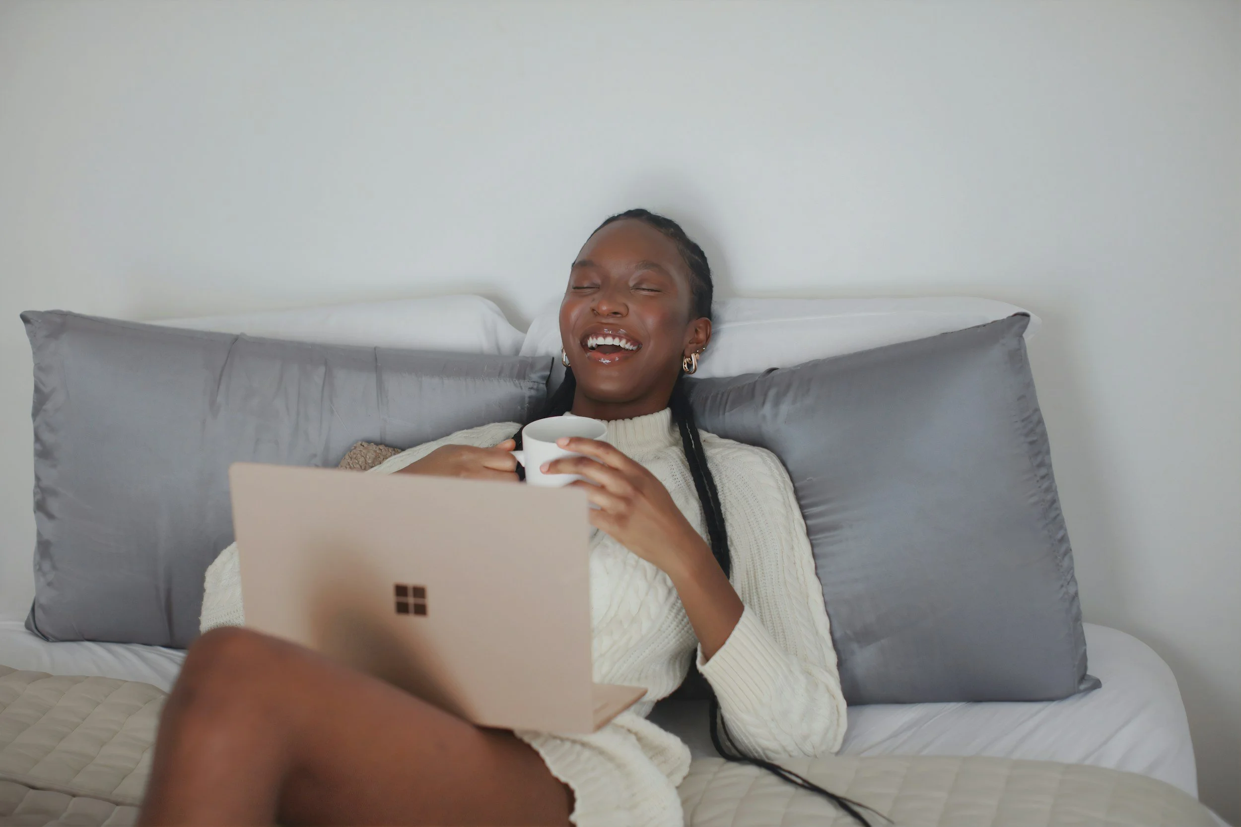 A pregnant woman on a video call looking happy and content