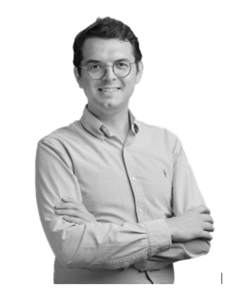 Portrait en noir et blanc d'une femme souriante, portant un blazer et une chemise simple.