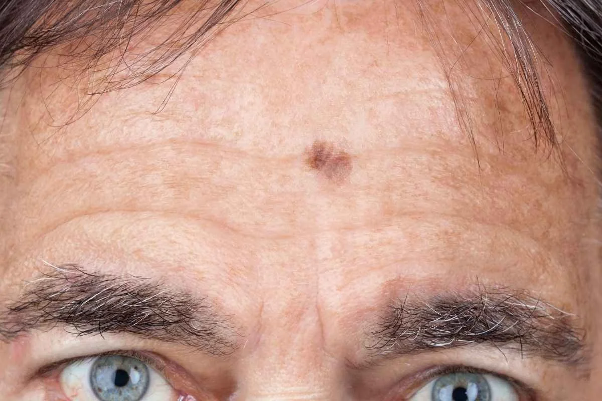 Close-up of a person's chest with a finger touching just below the collarbone.