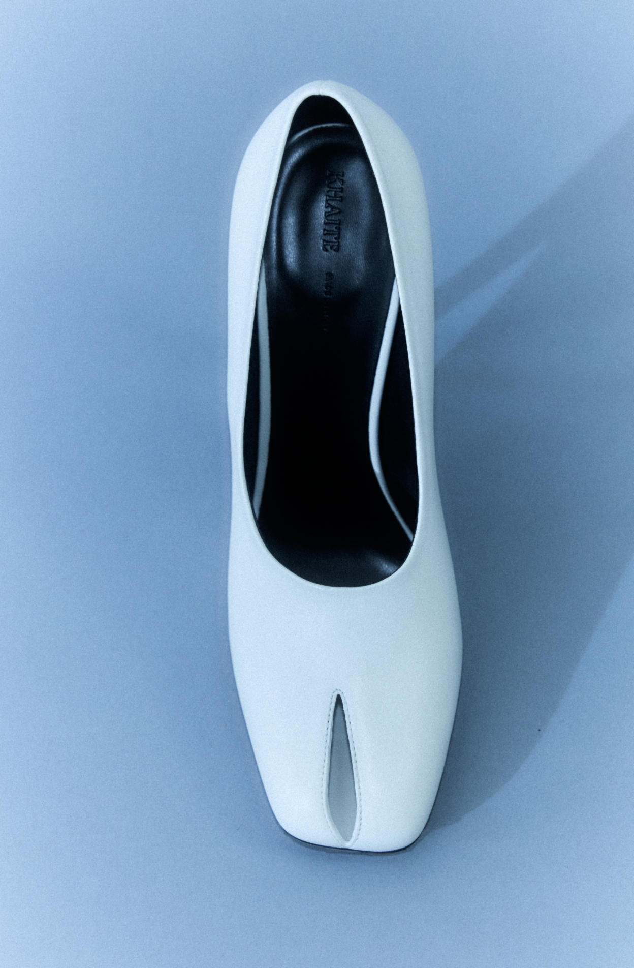 A white high-heeled shoe viewed from above against a blue background.
