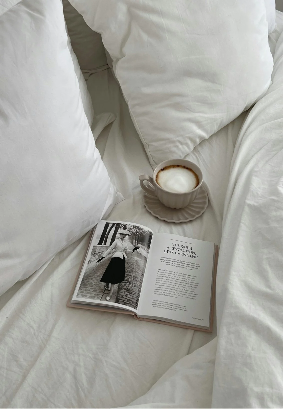 A white bed with pillows, an open magazine and a cup with cappuccino, representing the ease of doing couples therapy sessions from the comfort of home.