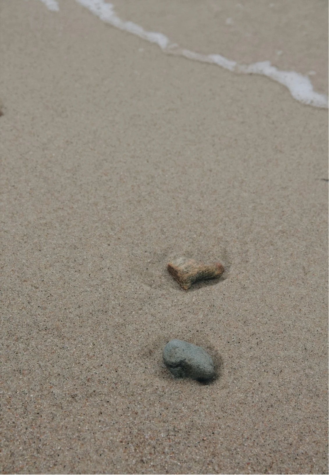 Close-up of sandy beach with small rocks, signifying a romantic relationship
