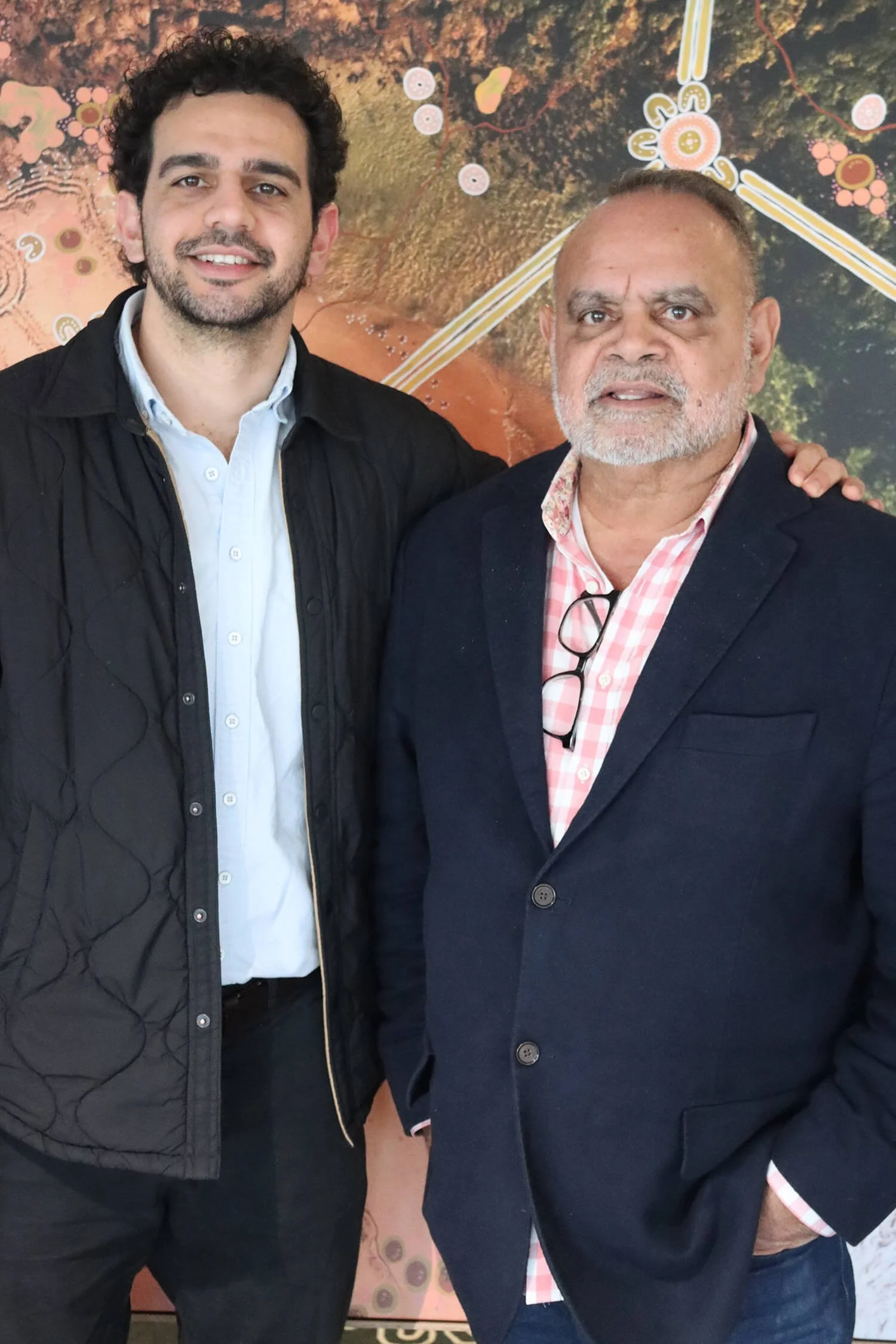 Jake and Michael Long stand next to each other. They are wearing business casual attire, with the man on the left in a black quilted jacket and the man on the right in a navy blazer.