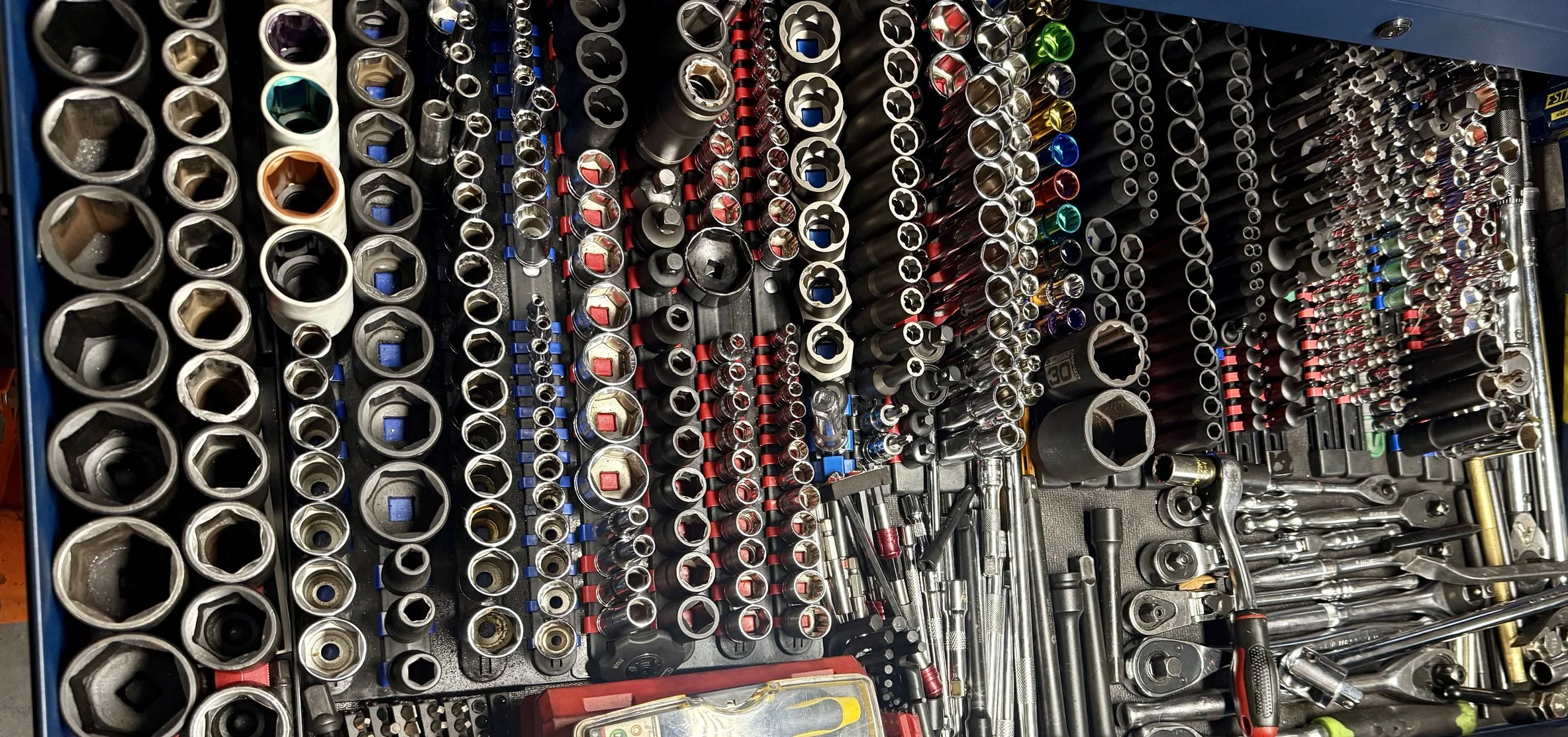 A variety of socket wrenches, ratchets, and tools organized on a tool grid, with different sizes and types, including allens and nut drivers.