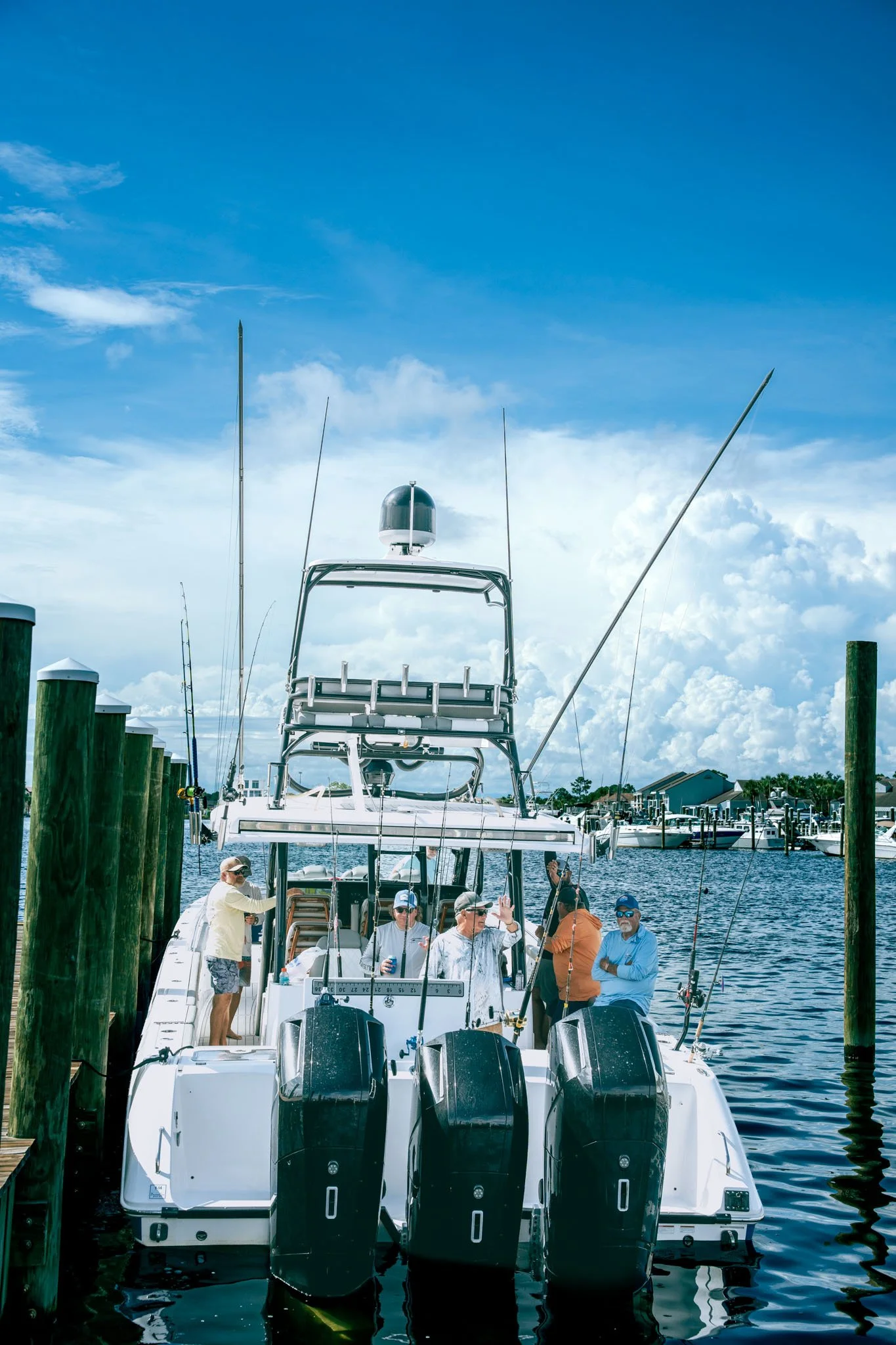 People standing on a boat docked at Point South Marina - Bay Point (Panama City Beach), with boats and water in the background.