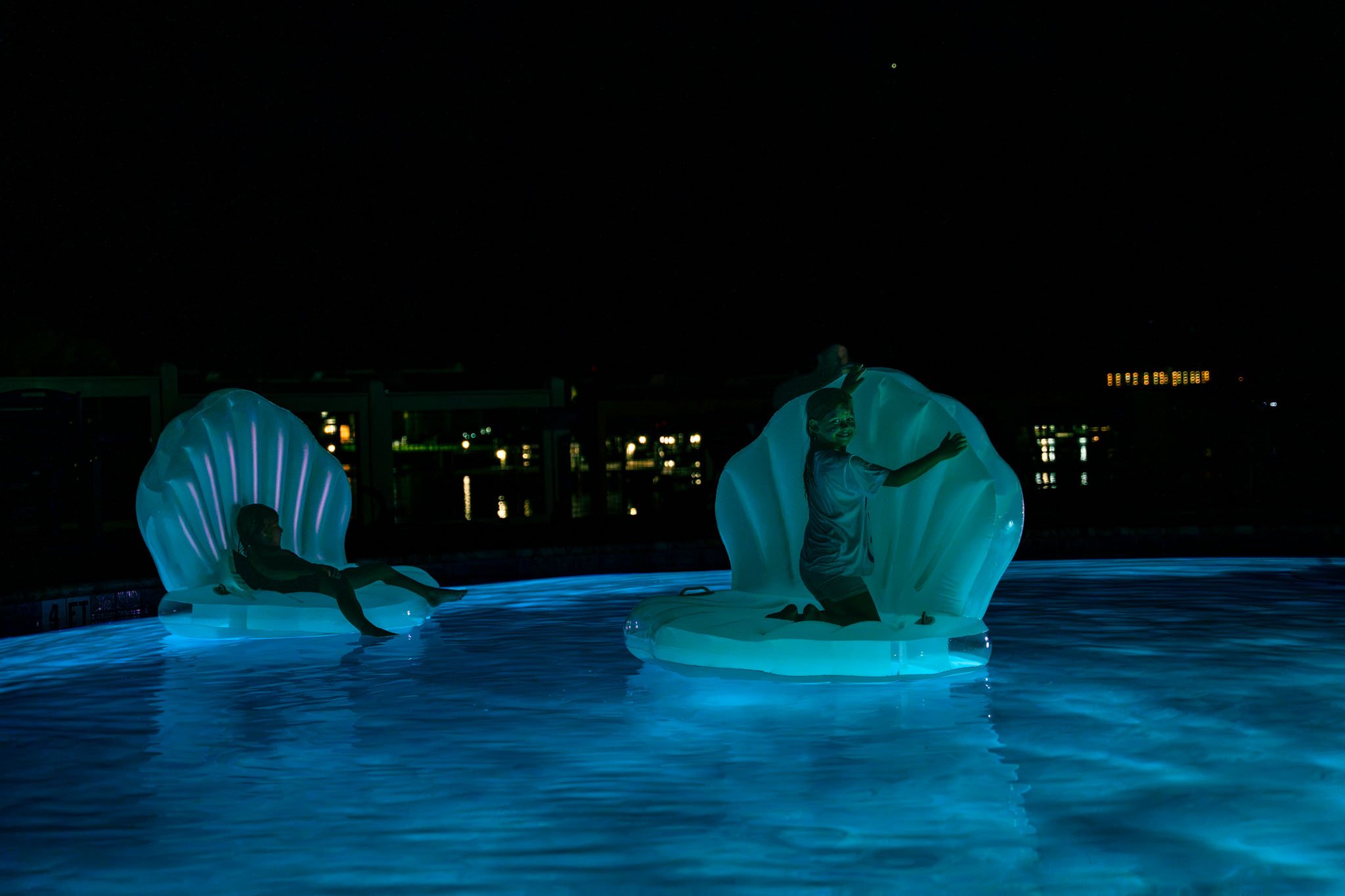 Nighttime scene at Point South Marina - Bay Point (Panama City Beach) pool with illuminated sculptures of children and seashell shapes.