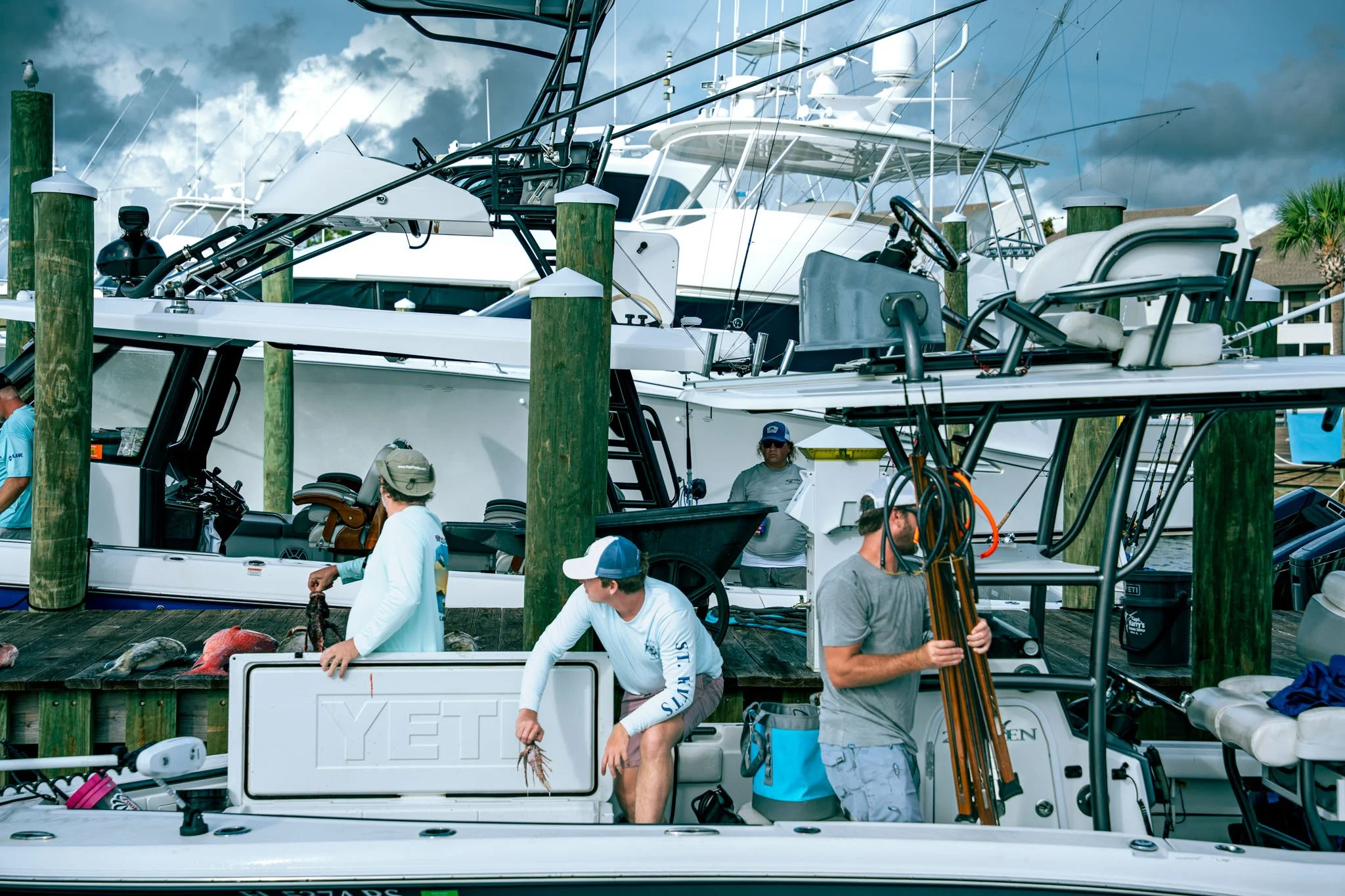 People preparing boats at Point South Marina - Bay Point (Panama City Beach) with multiple yachts docked and an overcast sky.