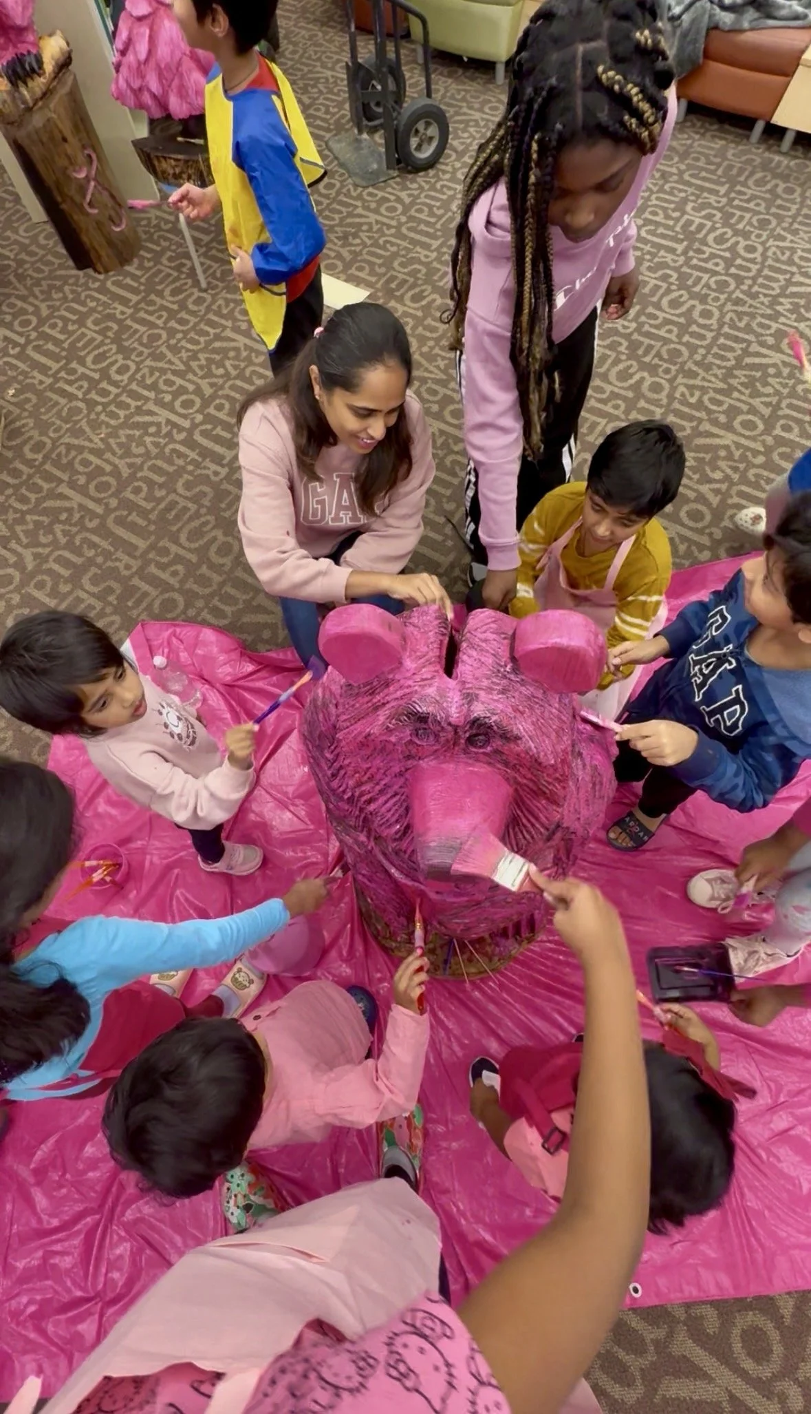 Children and an adult gathered around to paint Pynko pynk (pink).