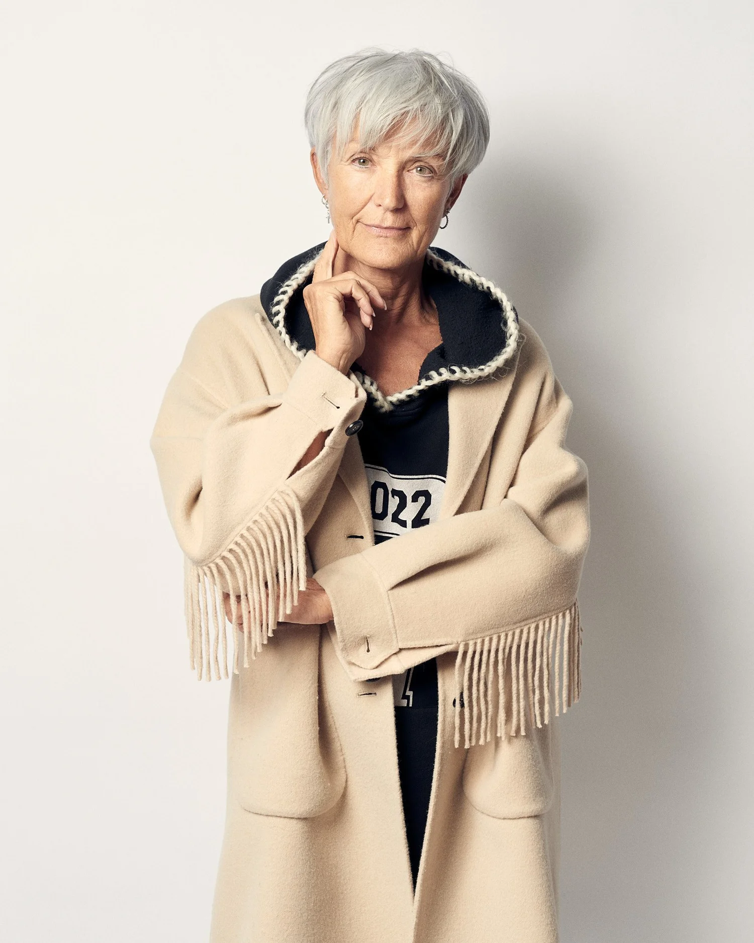 Näheres Porträt von Petra Mühleck im hellen Mantel, eine Hand am Kinn.