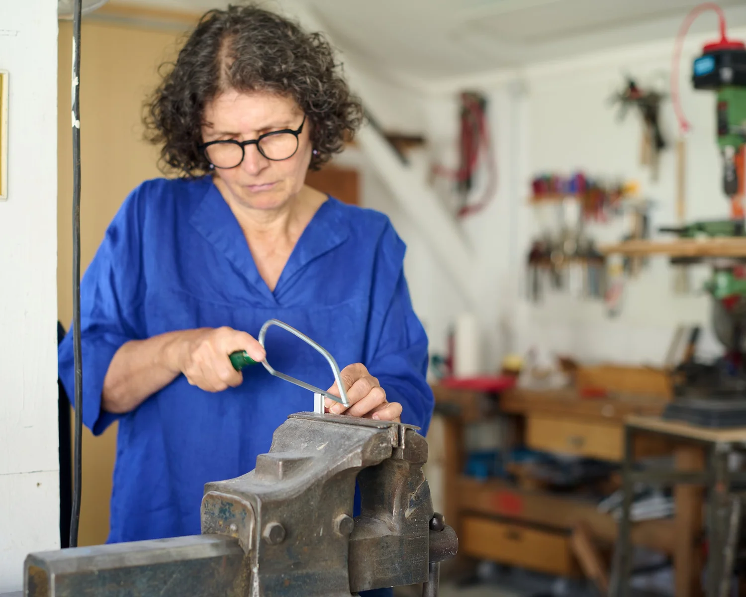 Elisabeth Heindl bearbeitet in ihrer Werkstatt ein eingespanntes Werkstück mit einer Handsäge.