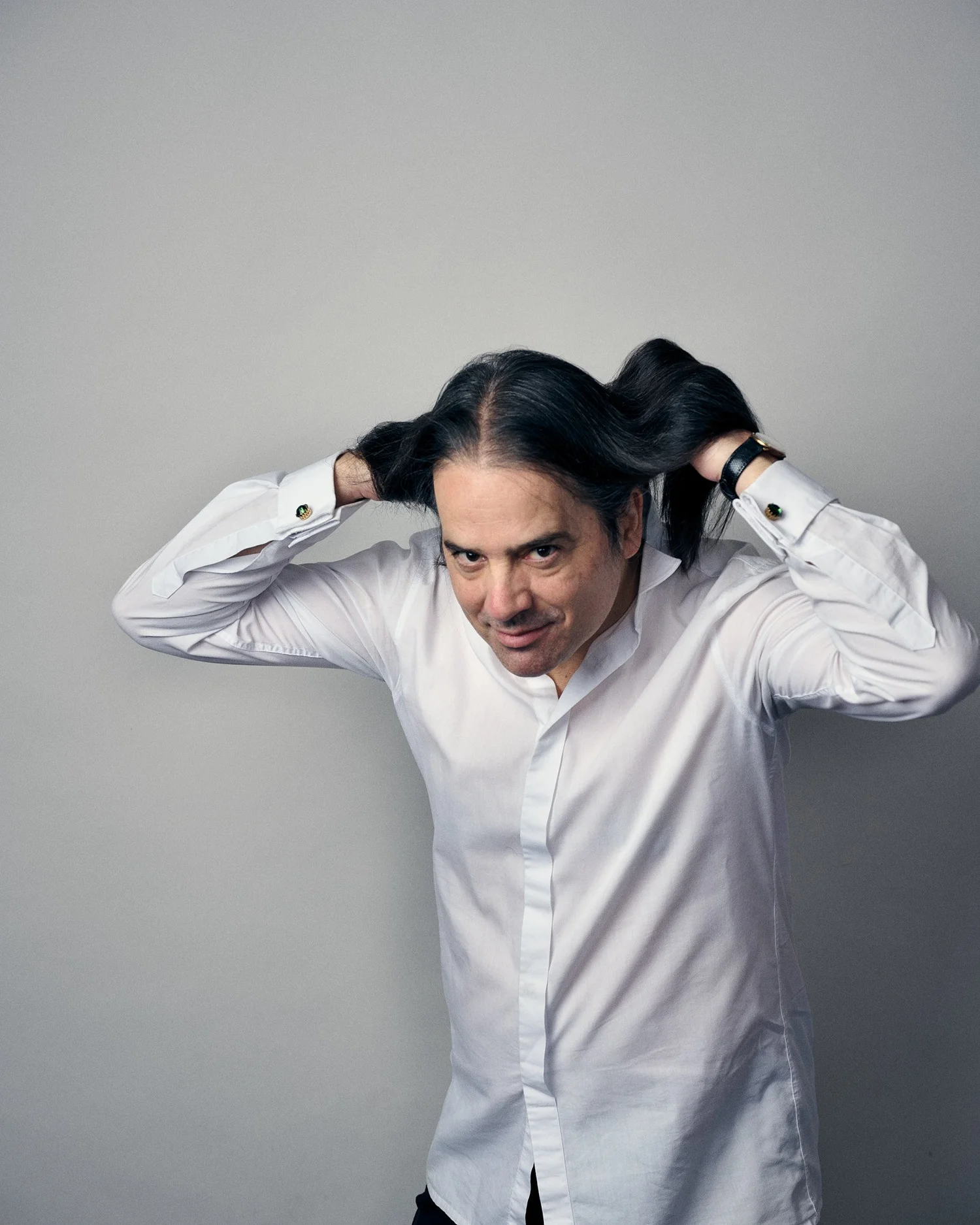Nikolai Vogel fährt sich mit beiden Händen durch die Haare und blickt in die Kamera.