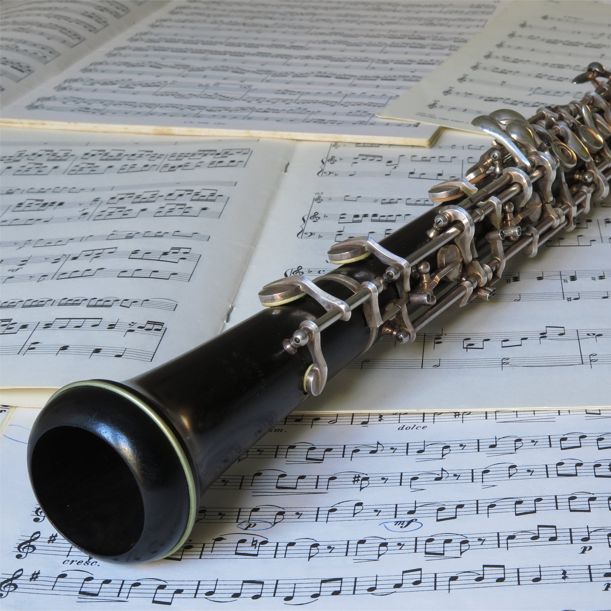 A black flute resting on sheet music pages with musical notes and symbols.