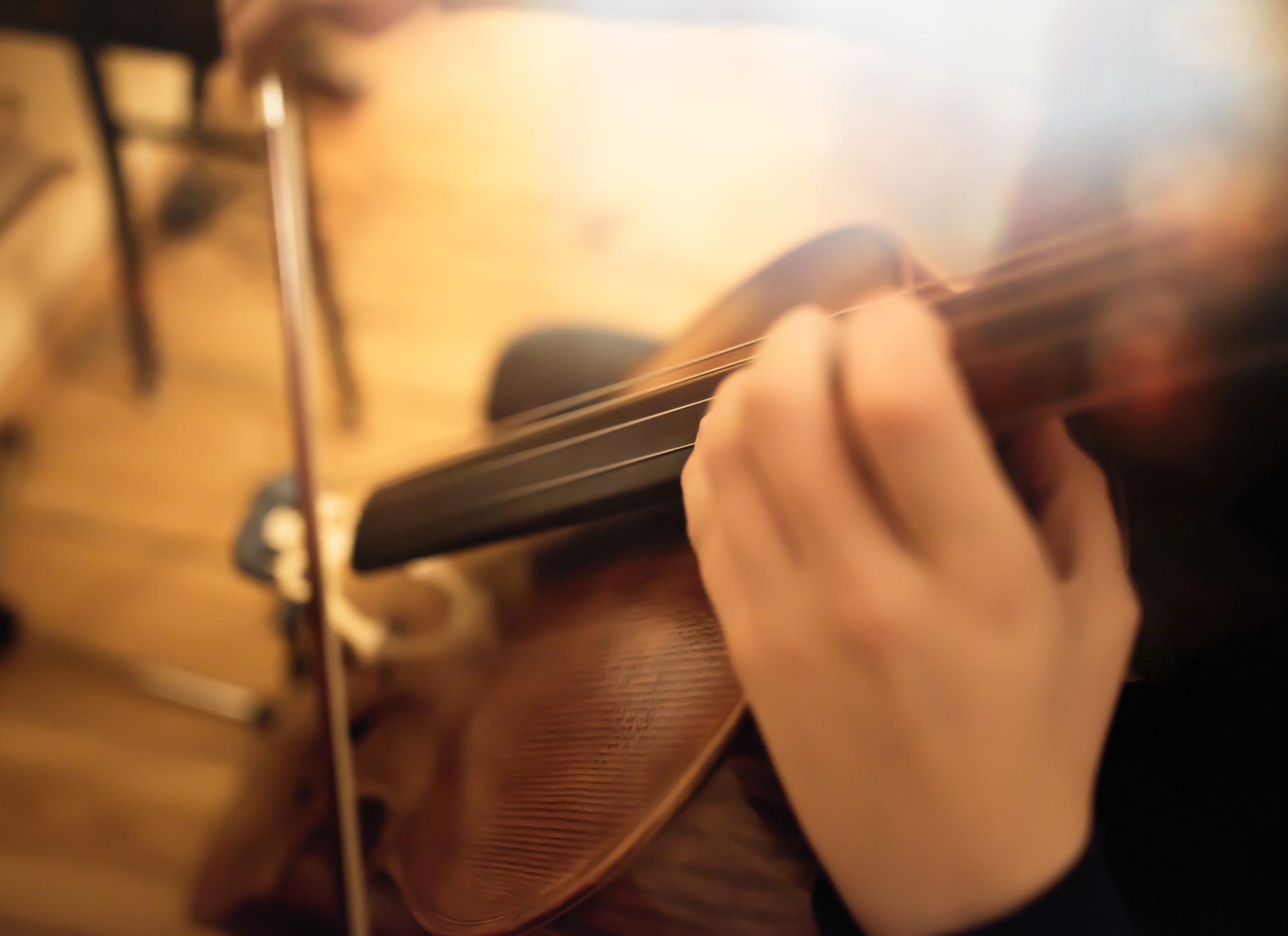Close-up of a person playing an acoustic guitar, focusing on their hand on the fretboard, with the background blurred.