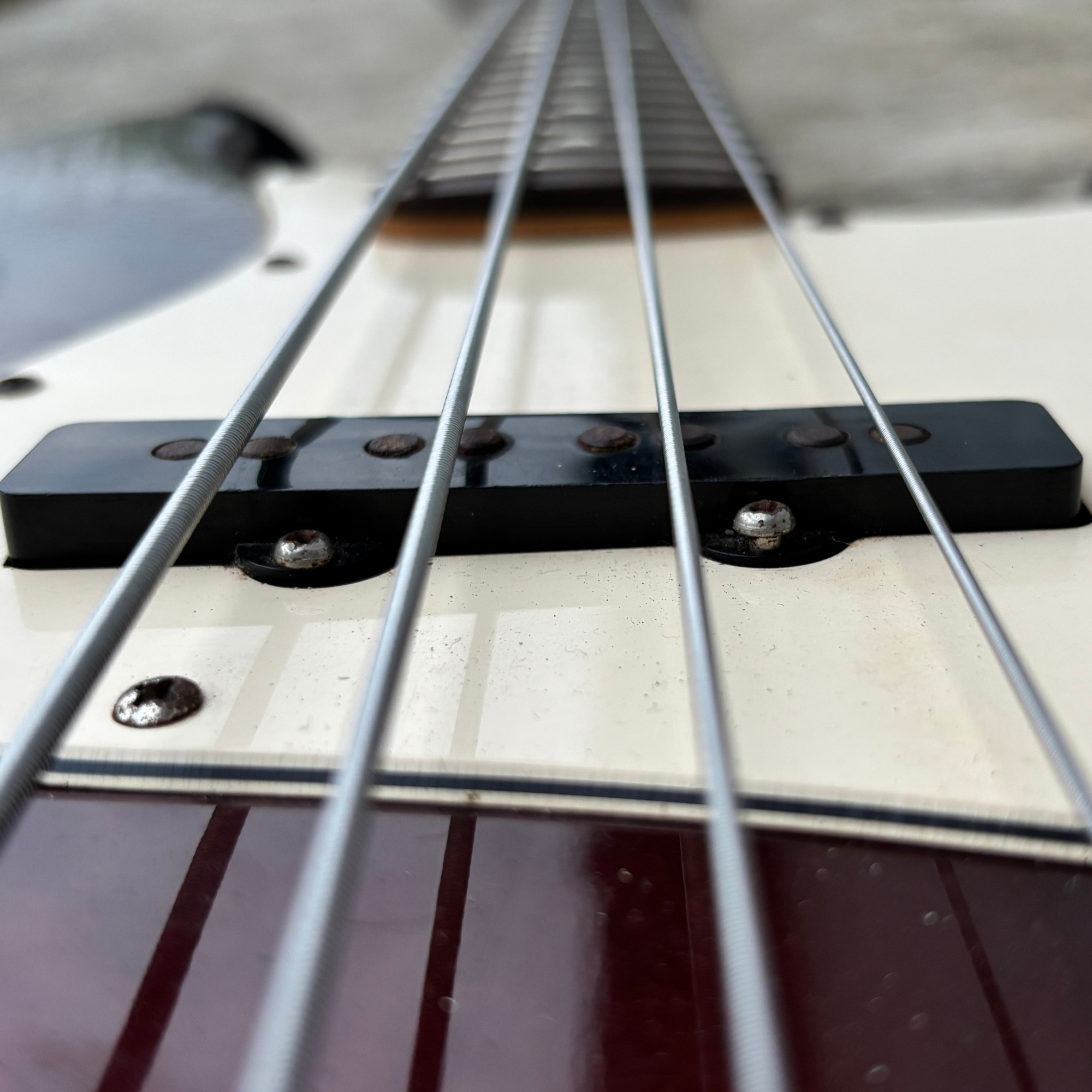 Close-up view of a guitar body with strings, bridge, and pickups visible, shot from the player's perspective.