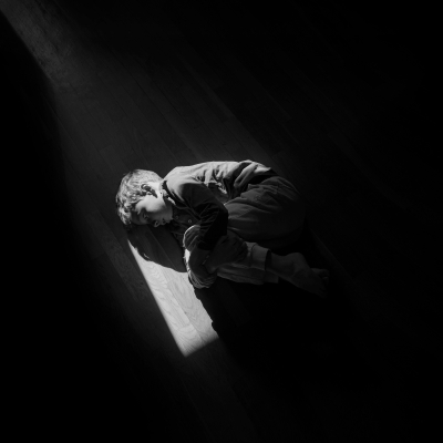 Black and white image of boy on the floor in fetal position