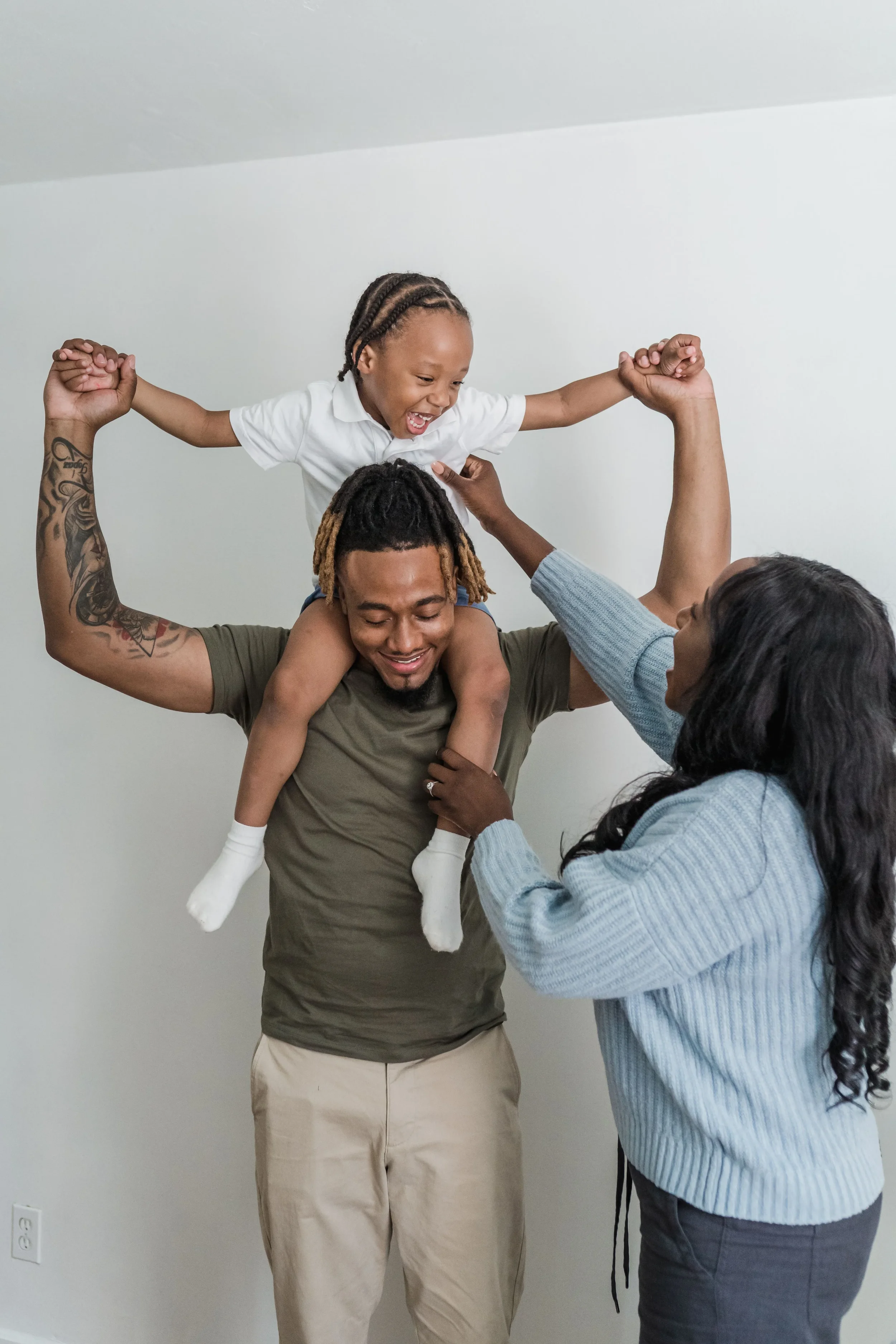 Man holding child on his shoulders with mom next to them holding childs hand