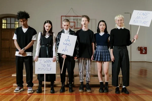 Group of teens standing in a gym holding signs