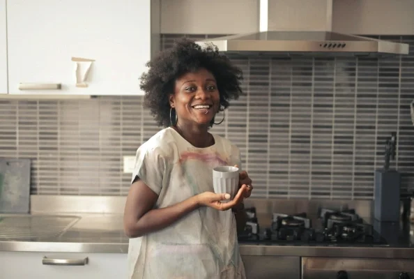 Woman smiling while holding coffee mug in a kitching