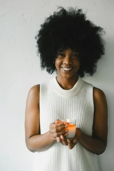 Happy woman holding a candle jar in her hands