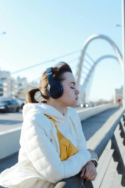 Woman wearing headphones standing at railing