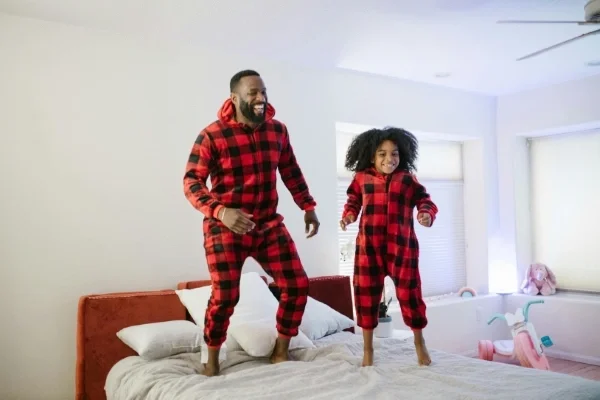 Man and child in matching pajamas jumping on bed