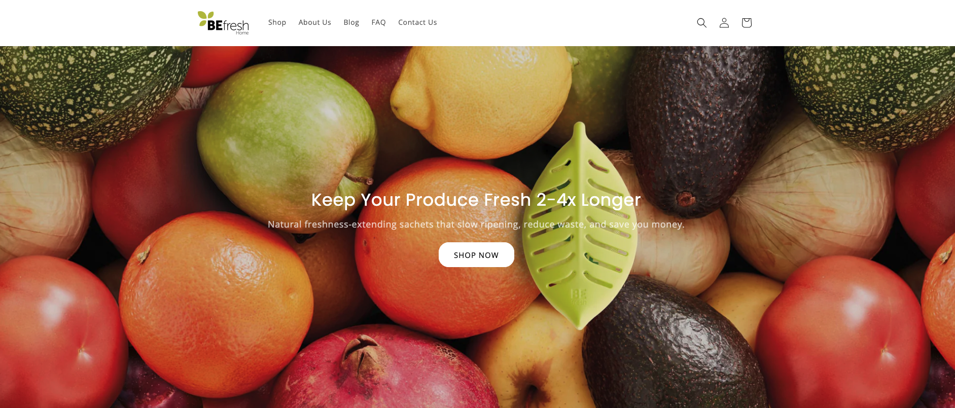 A webpage homepage for BEfresh Home featuring an array of fresh fruits including apples, oranges, lemons, avocados, and tomatoes. The page highlights keeping produce fresh 2-4 times longer with natural sachets. It has a navigation menu at the top, a search icon, user account icon, shopping cart icon, and a central call-to-action button labeled 'Shop Now'.