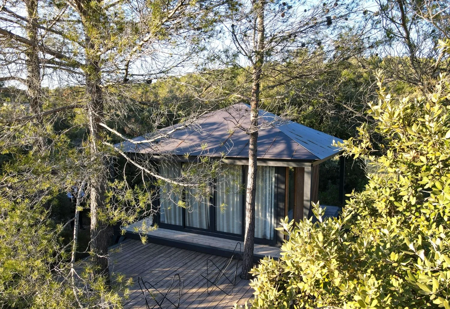Ecolodge KOBE entourée d'arbres, vue depuis une terrasse en bois.