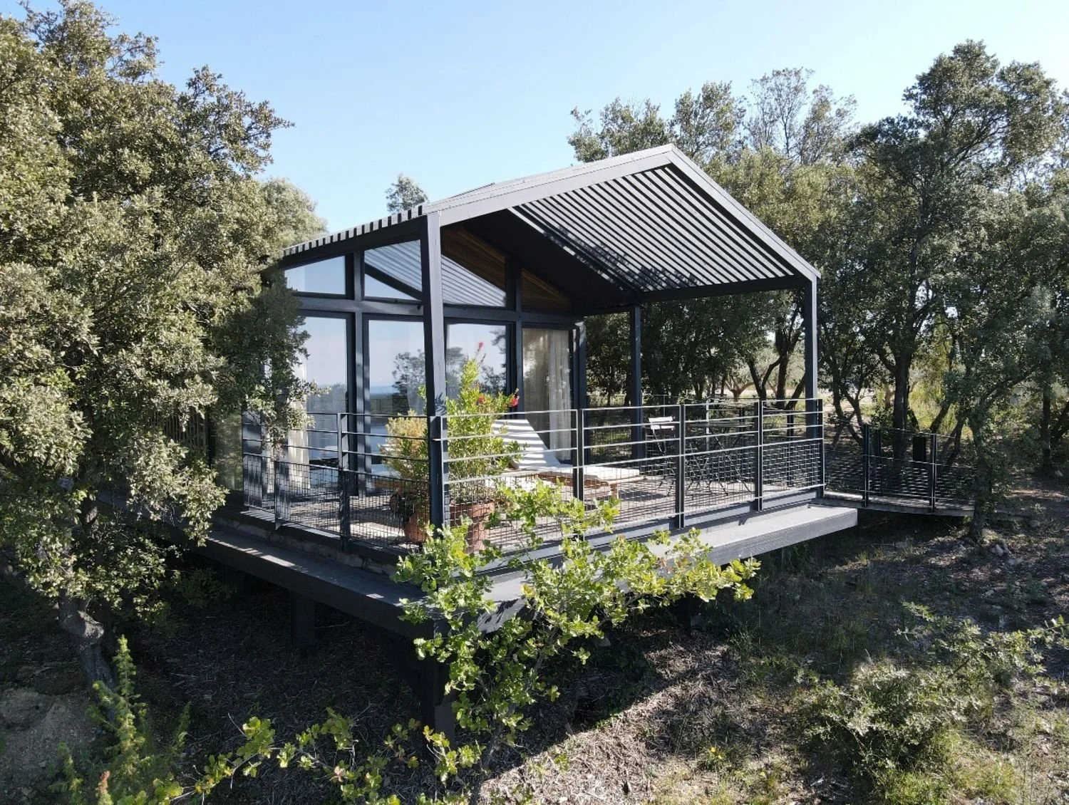 Ecolodge KOYA avec un balcon surélevé entouré d'arbres sous un ciel clair.
