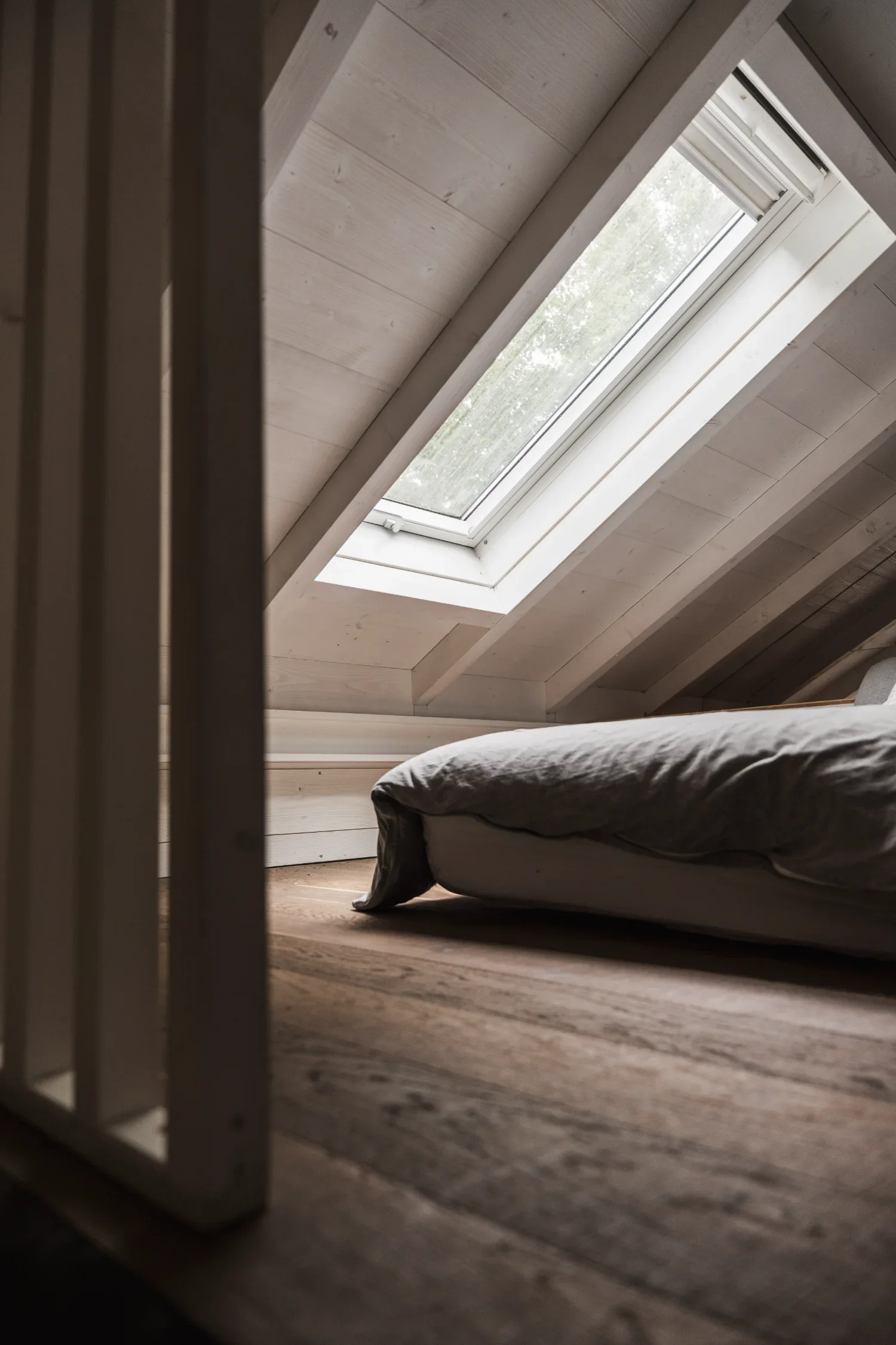 Vue d'un Ecolodge TESHIMA avec un lit plié et un plafond en bois avec une lucarne.