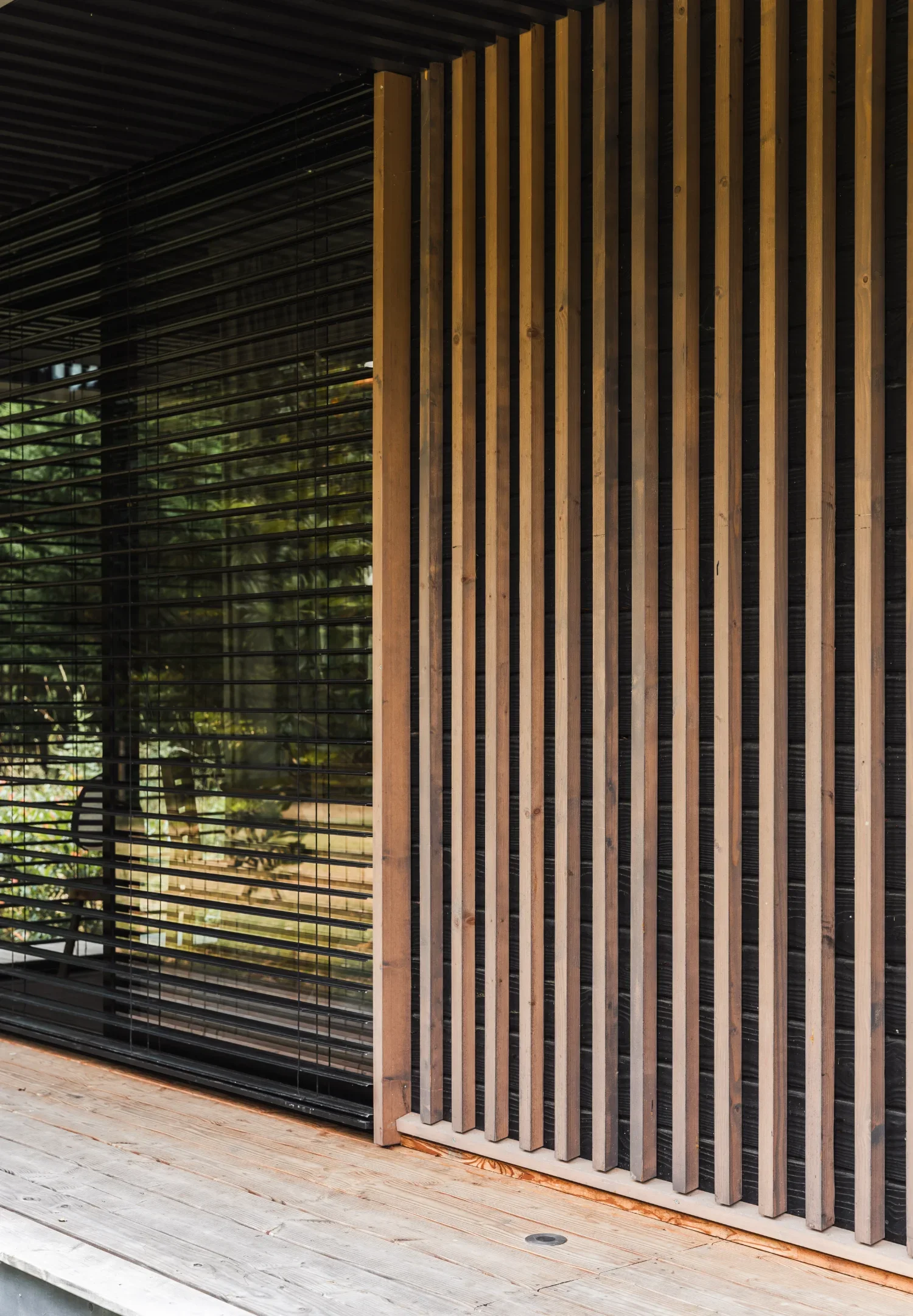 Vue d'une façade moderne avec des lattes de bois verticales et des volets en lamelles de bois d'un Ecolodge TESHIMA