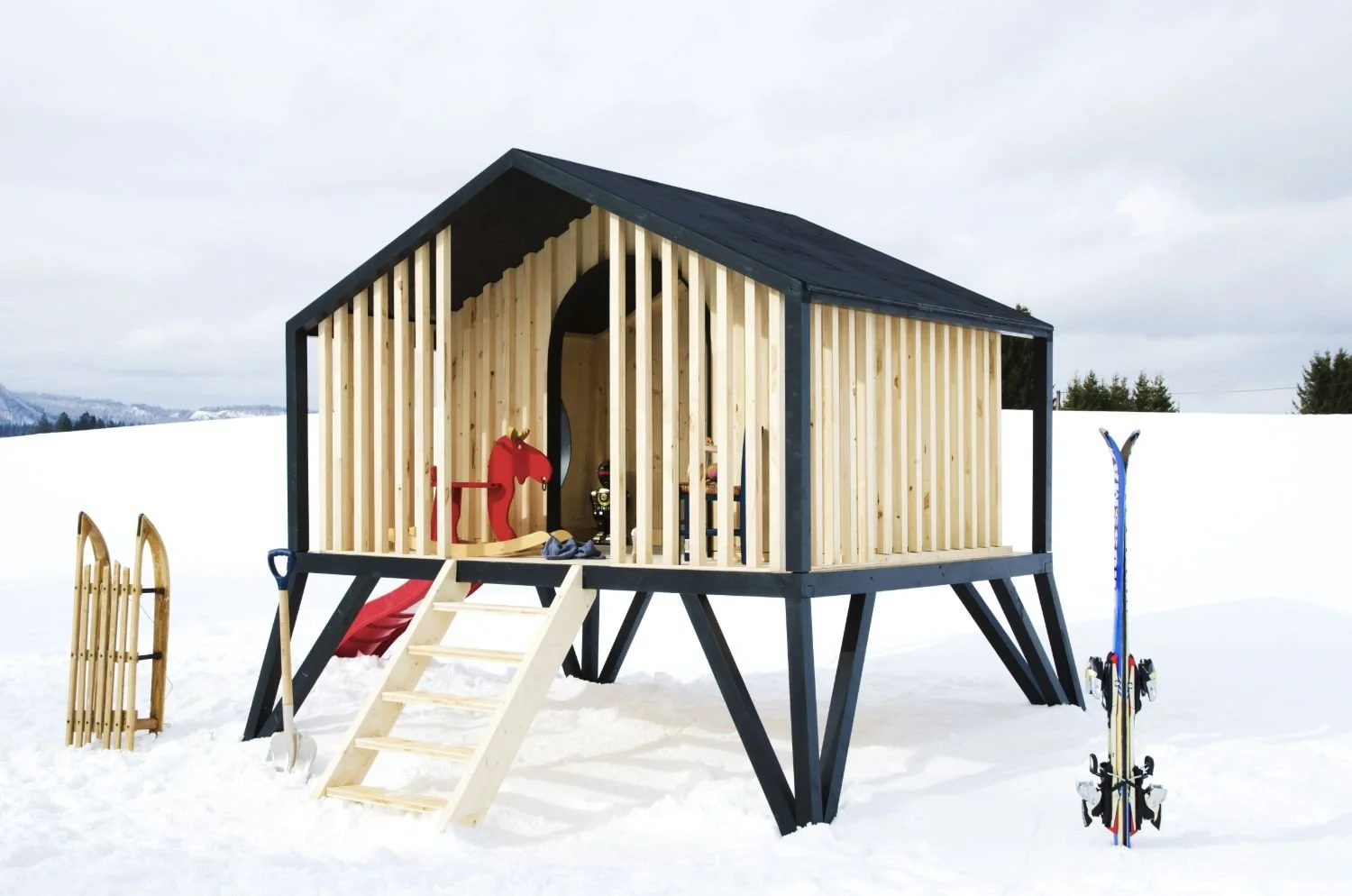 Cabane d'enfant en bois dans la neige avec accessoires de ski et luge