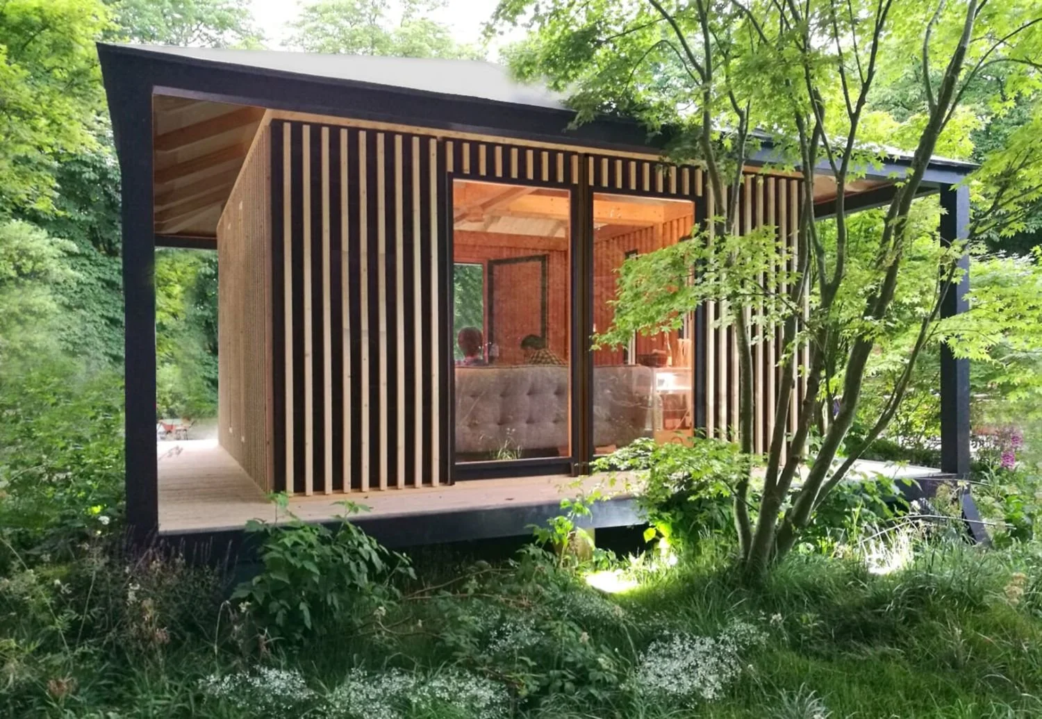 Ecolodge KOBE entourée de verdure et d'arbres, avec de grandes fenêtres et un balcon en bois.