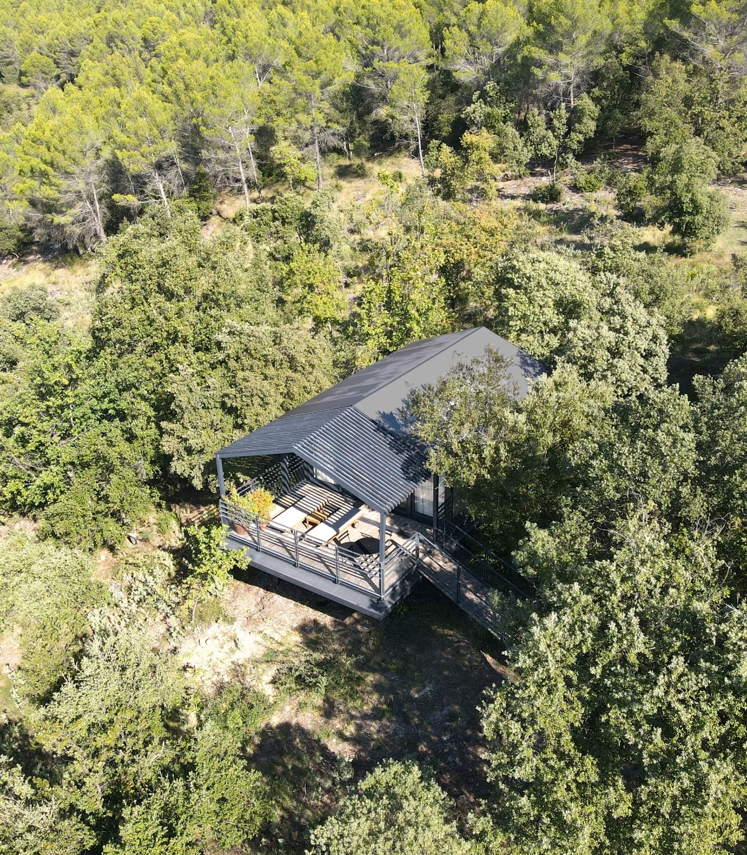 Une maison en bois construite dans la forêt, avec une terrasse en bois entourée de barrière, dissimulée parmi les arbres.