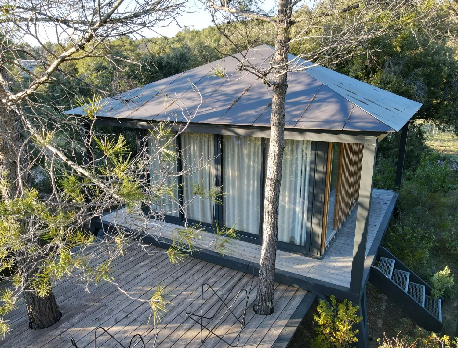 Ecolodge KOBE avec une terrasse en bois, entourée d'arbres, vue en hauteur.