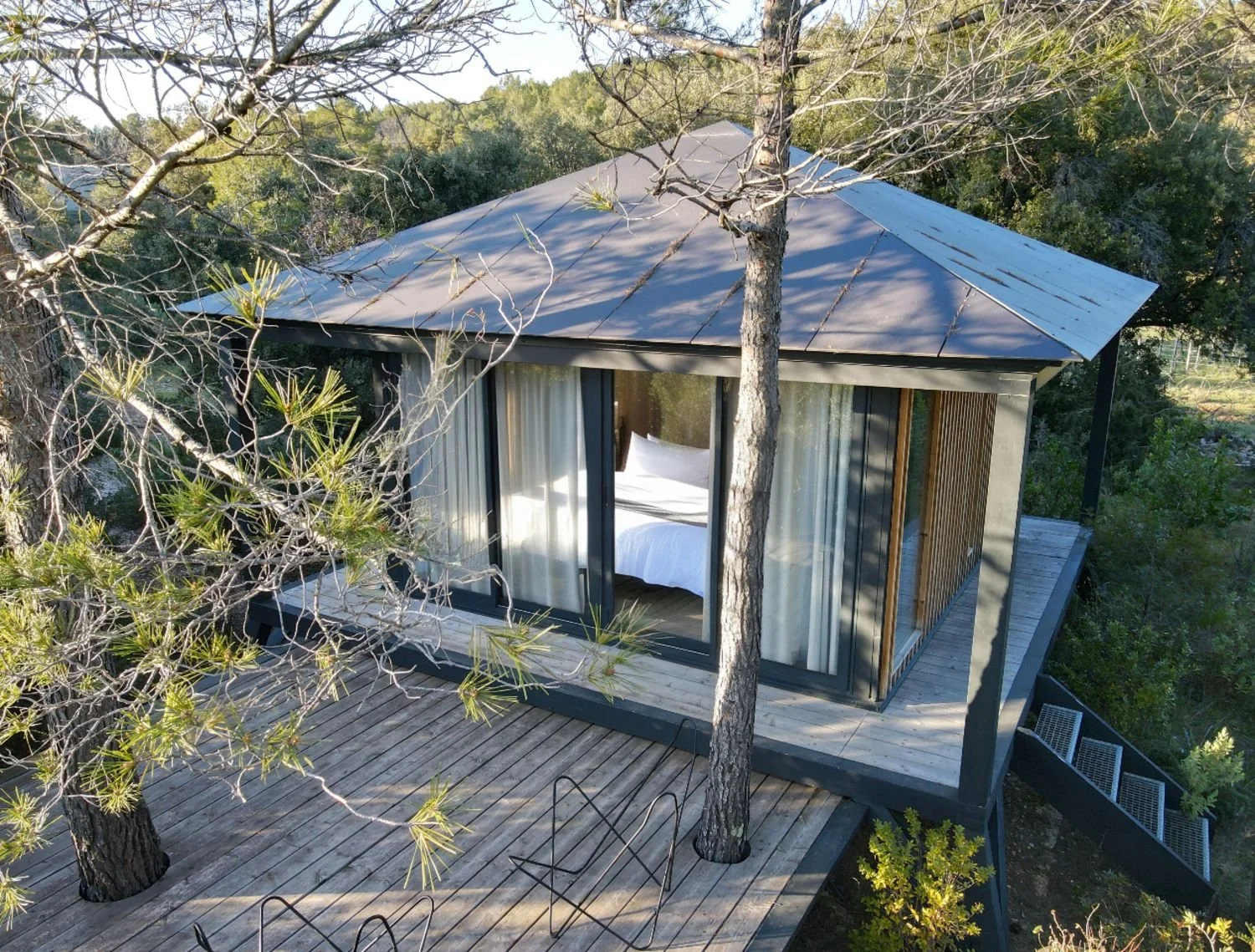 Ecolodge KOBE avec terrasse en bois, entourée d'arbres, vue aérienne