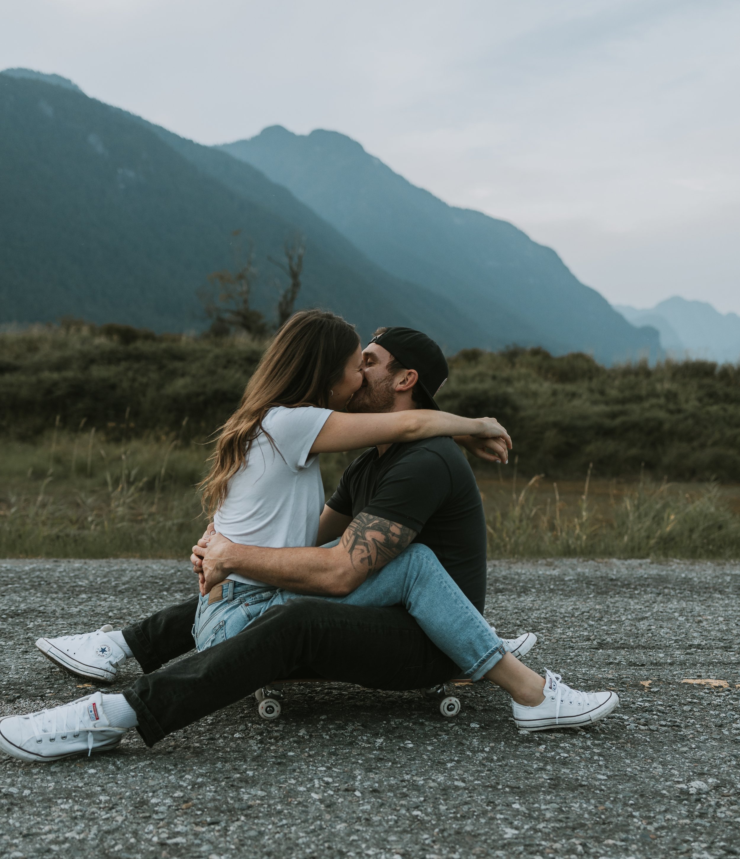 Engaged couple riding a skateboard together during their engagement session at Pitt Lake, British Columbia, photographed by Alberta & BC engagement photographer Shannon Boyd