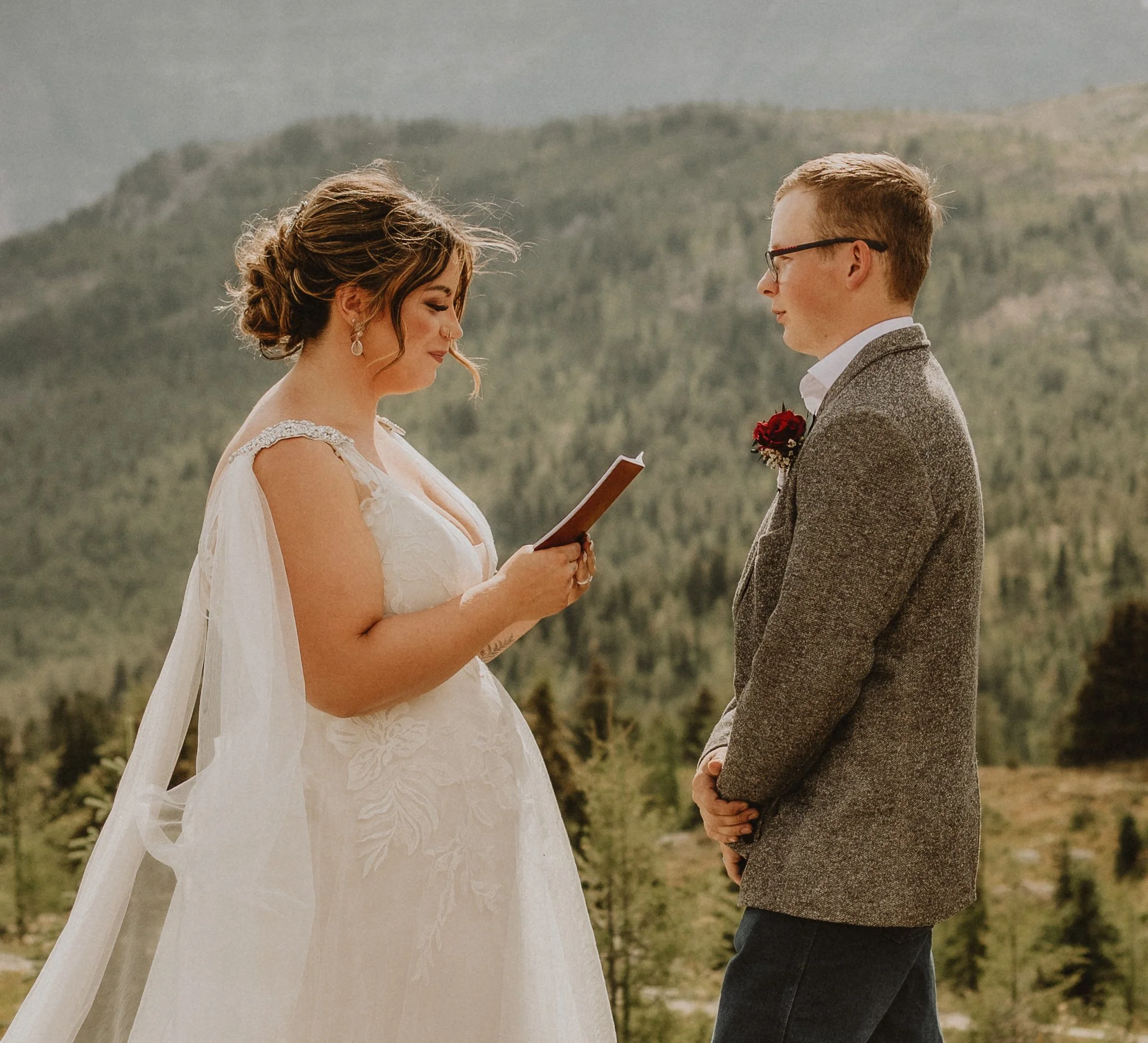 Bride and groom reading their vows on top of a mountain in Banff, Alberta during their elopement, photographed by Calgary & Alberta elopement photographer Shannon Boyd