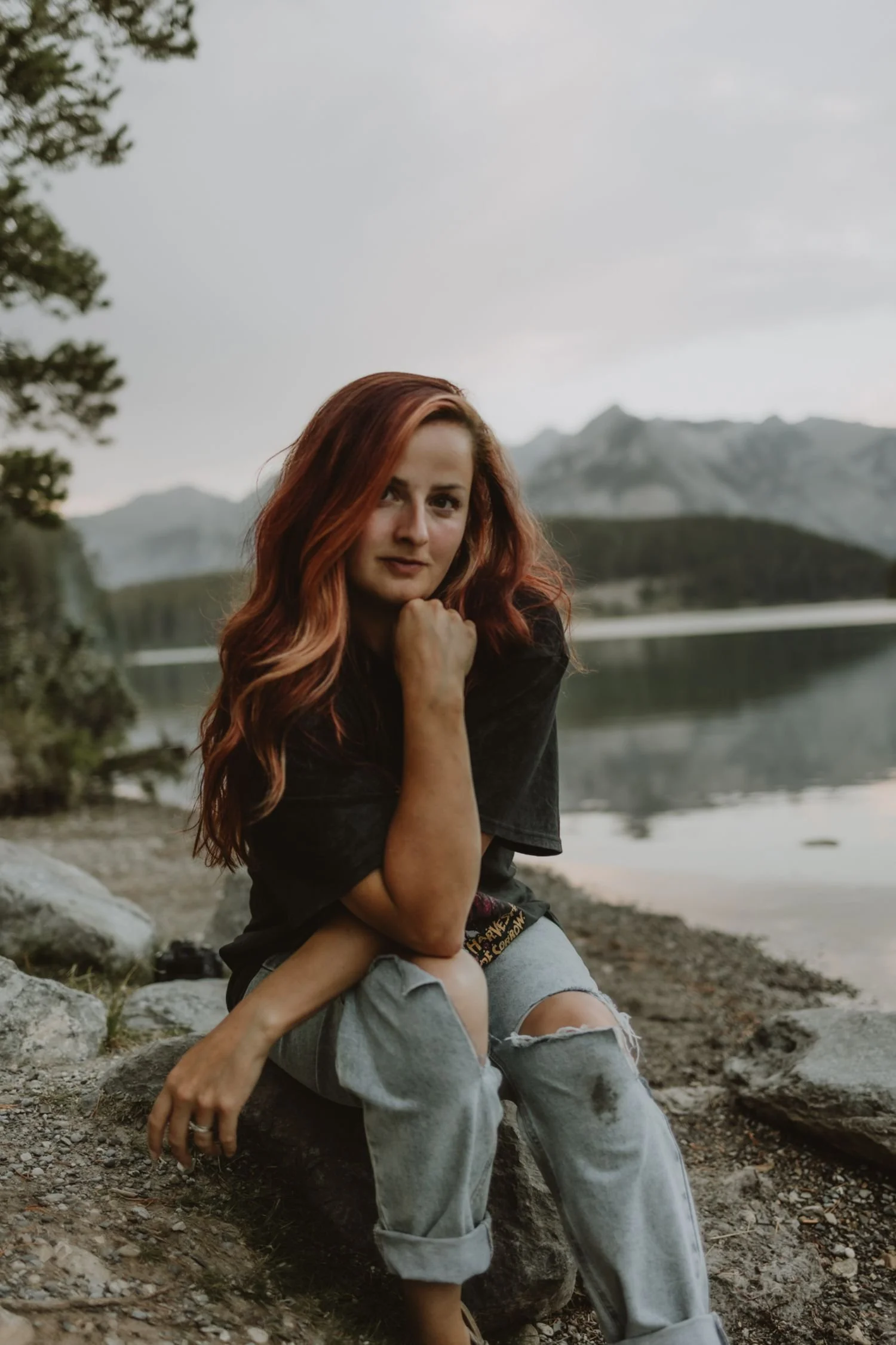 Shannon Boyd, Calgary & Alberta elopement photographer, sitting on a rock with Two Jack Lake and the Banff mountains in the background