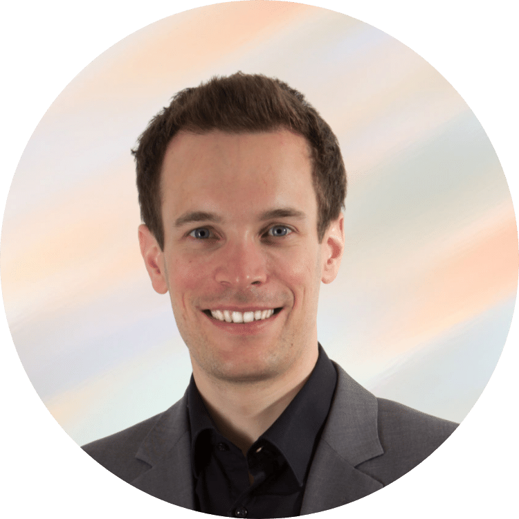 Porträt eines jungen Mannes in Geschäftskleidung vor einem farbigen Himmelshintergrund.