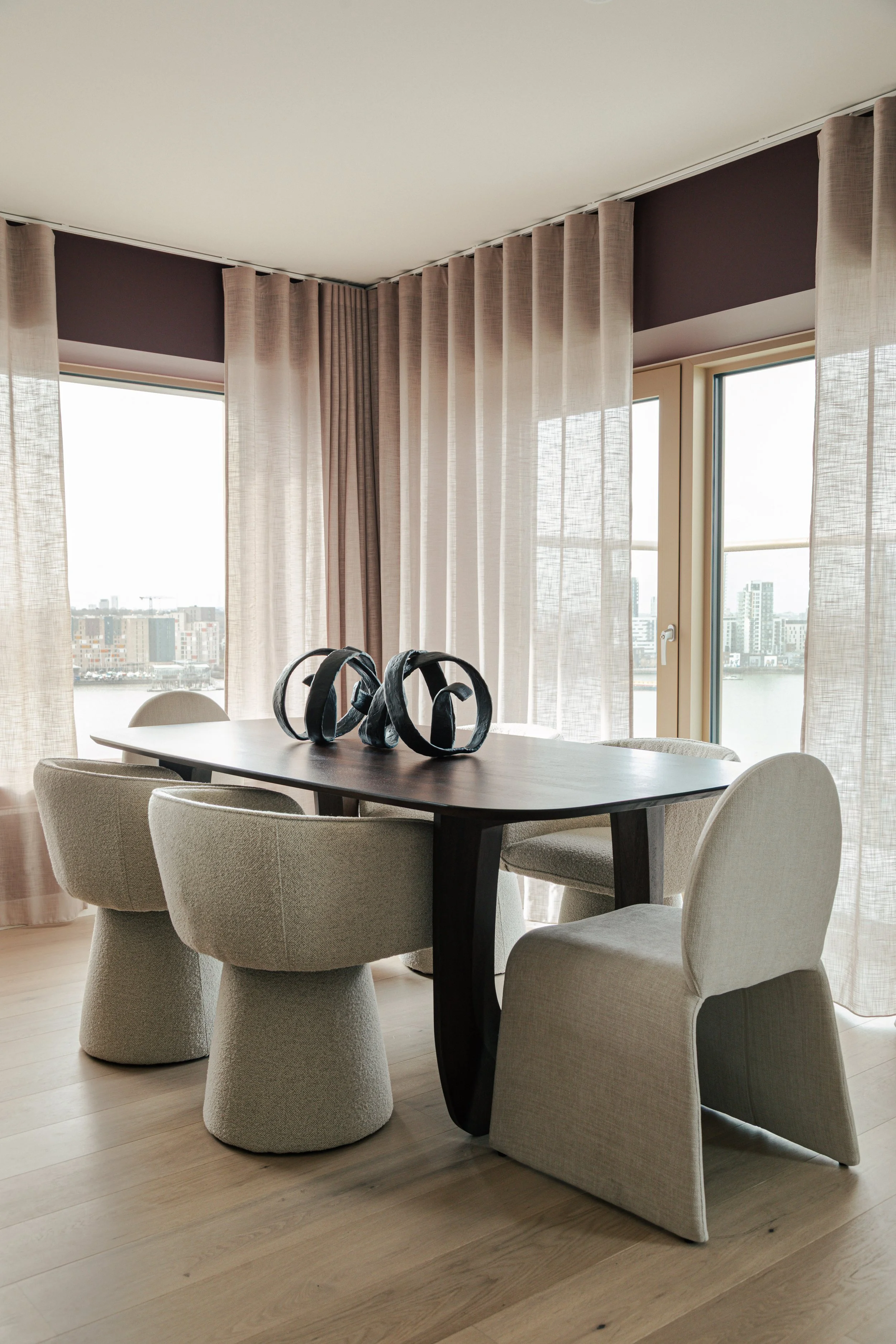 Close-up of a patterned beige and brown rug, cream curtains, and wooden door frame.
