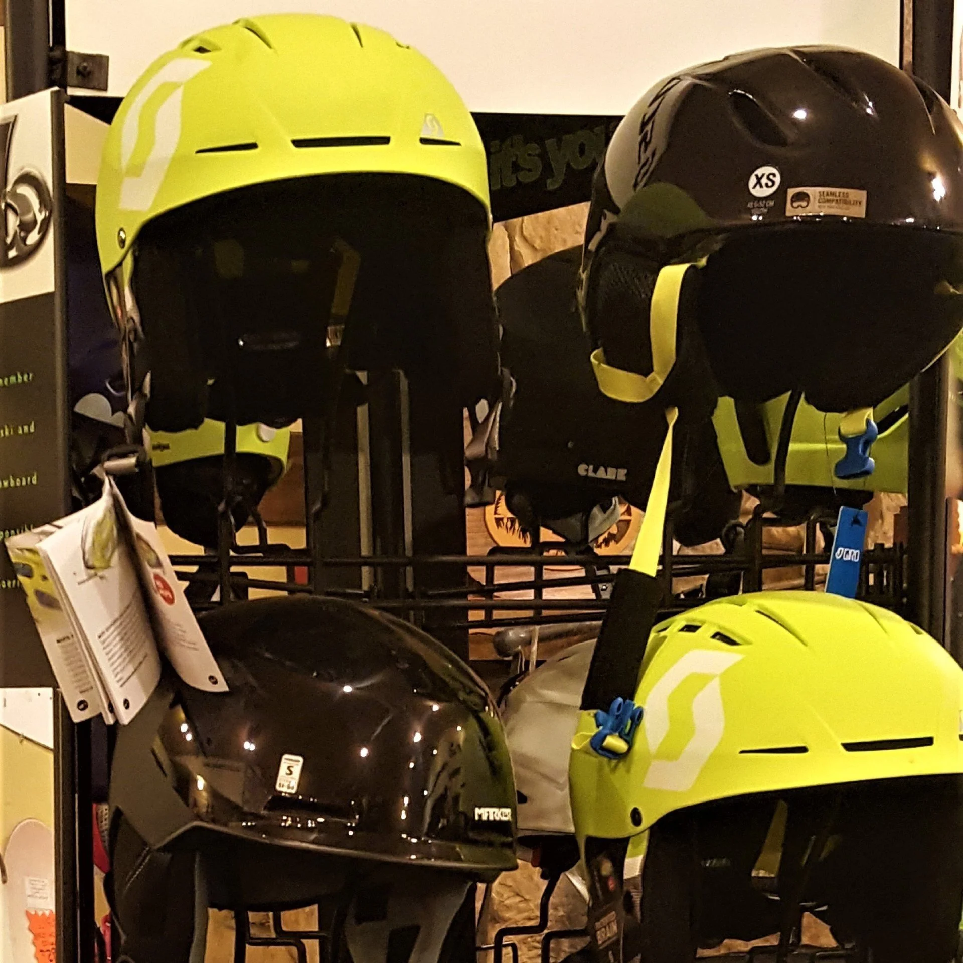 Display of multiple bike helmets in black and yellow colors on a store rack.