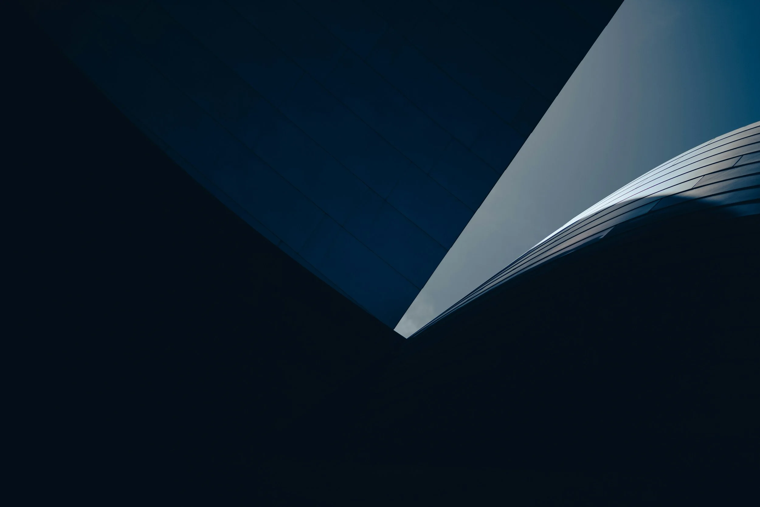 Close-up of a modern building with reflective glass windows, captured from an upward angle.