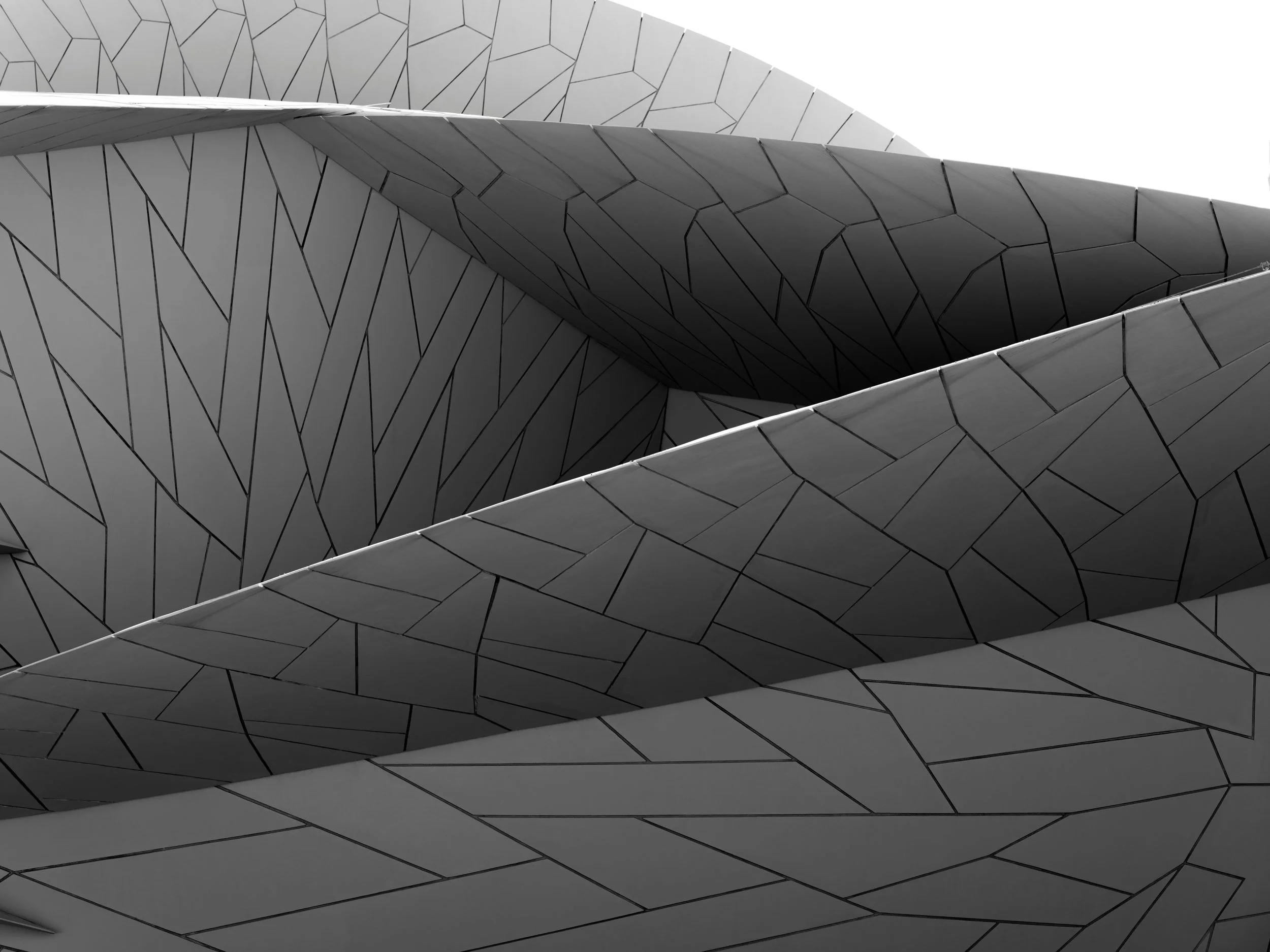 Close-up of modern architectural building with curved, overlapping metal panels with geometric pattern in black and white.