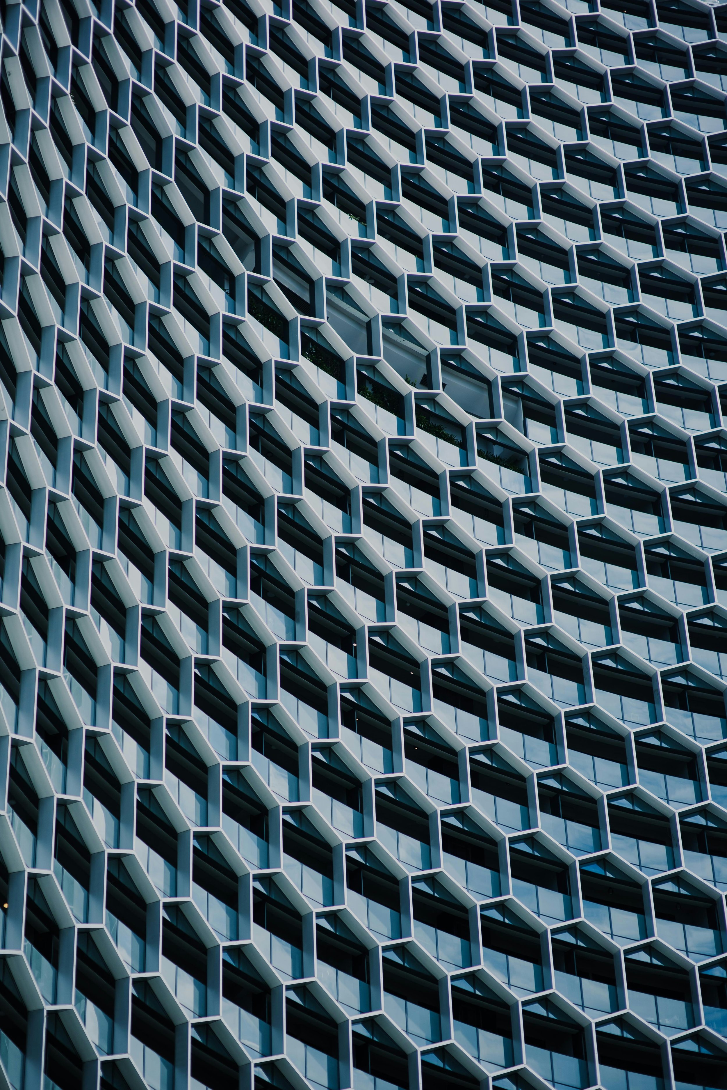 Close-up view of a modern building's facade with a geometric honeycomb pattern made of glass and metal.
